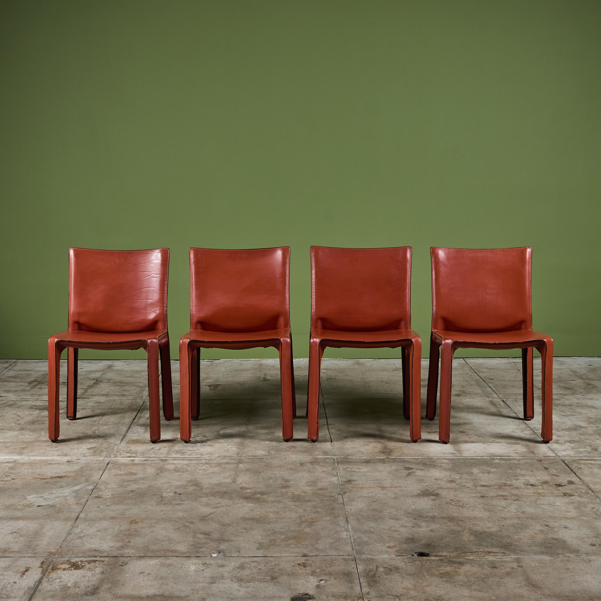 The iconic chairs designed by Mario Bellini for Cassina c.1970s, Italy, feature the original red saddle leather which is wrapped atop the steel frames. The back legs feature a black zippered detail. The chairs can easily be used for dining or an