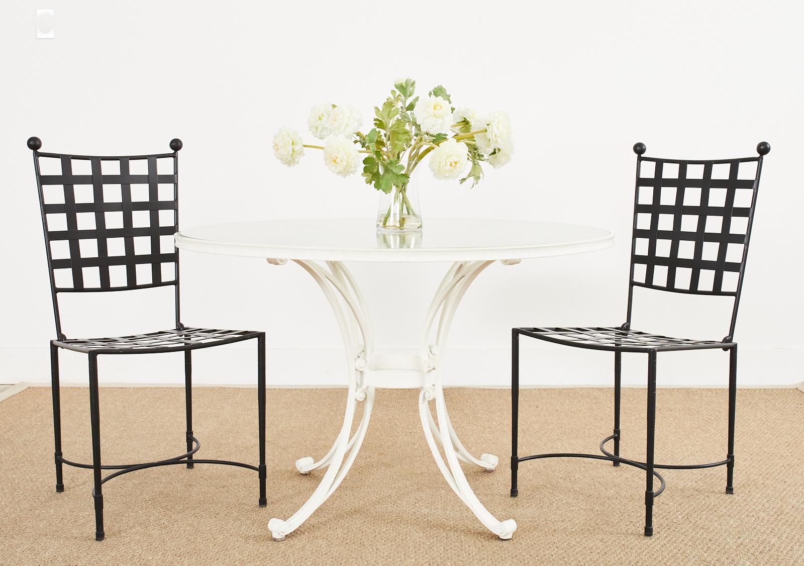 Iconic set of four iron patio and garden dining chairs made in the style and manner of Mario Papperzini for John Salterini. Classic Mid-Century Modern design featuring a lattice seat and back with ball finials on the top corners. The sturdy legs are