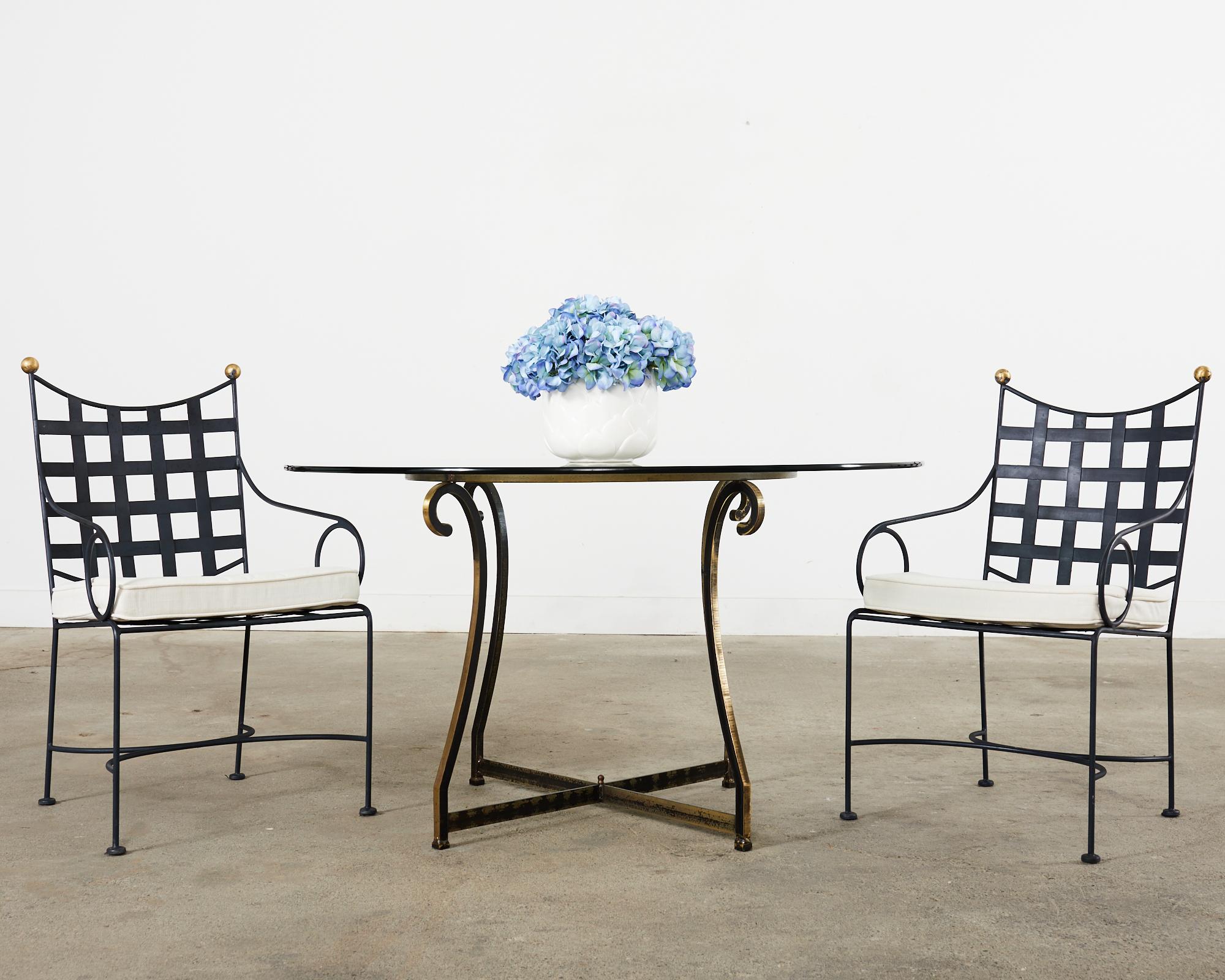 Iconic mid-century modern set of four patio and garden dining armchairs made in the style and manner of Mario Papperzini for John Salterini. The chairs feature wrought iron frames with lattice seats and backs in the neoclassical style topped with