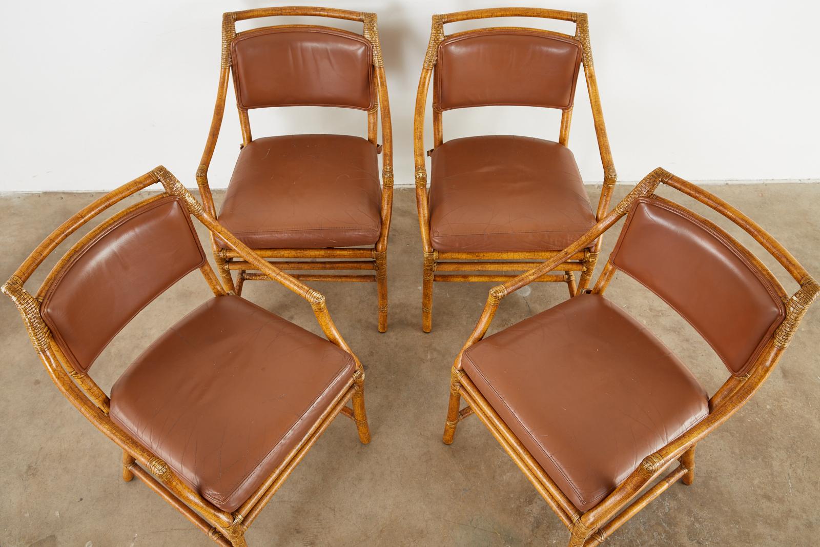 Bespoke set of four genuine McGuire bamboo rattan dining armchairs with leather upholstery. These chairs were custom ordered with a hand-applied craquelure lacquer finish for an intentionally aged look. Rarely seen optional finish from the McGuire