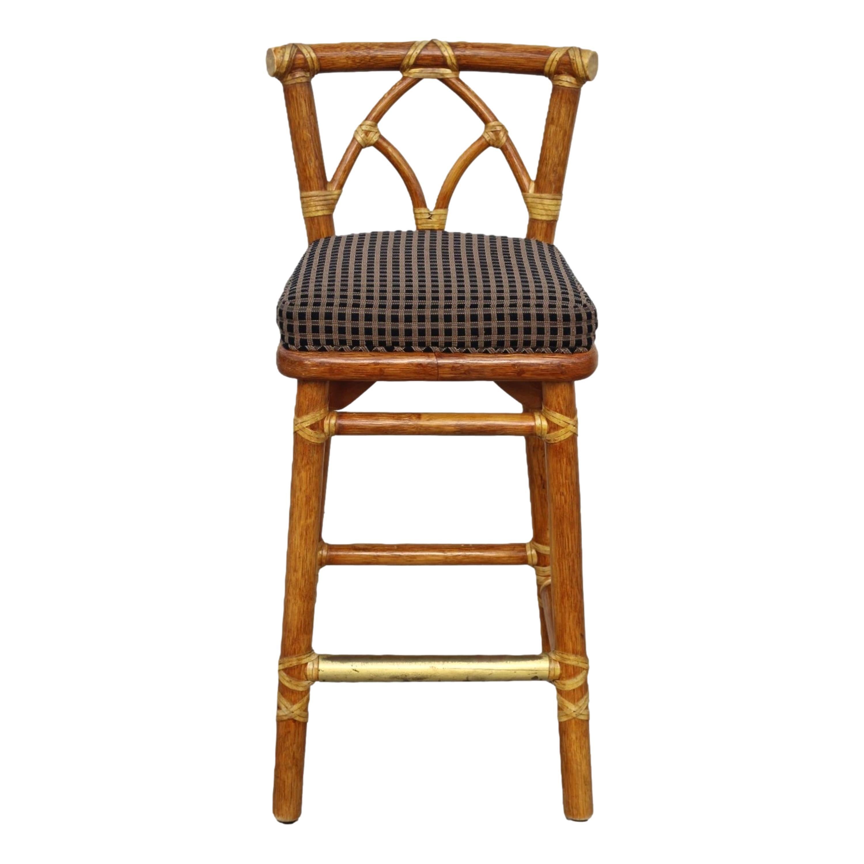 A set of four genuine McGuire handcrafted organic modern barstools, marked McGuire San Francisco. The stools feature thick rattan poles, a cathedral arch splat, and McGuire's signature laced rawhide on exposed joints. Gently flared legs are