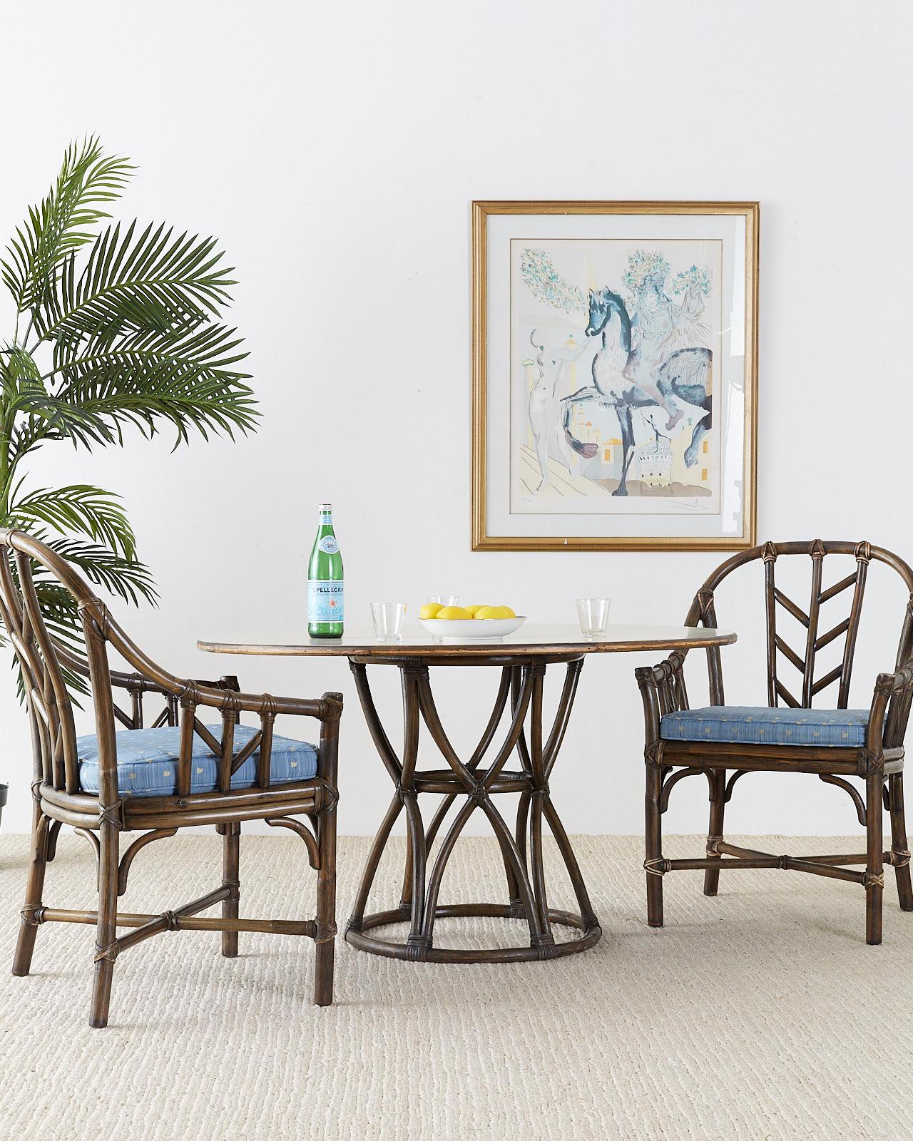 Distinctive set of four organic modern bamboo rattan dining chairs or armchairs made by McGuire. Features a thick rattan frame with a gracefully curved horseshoe style back. Decorated with an open fretwork design on the sides and back. Reinforced