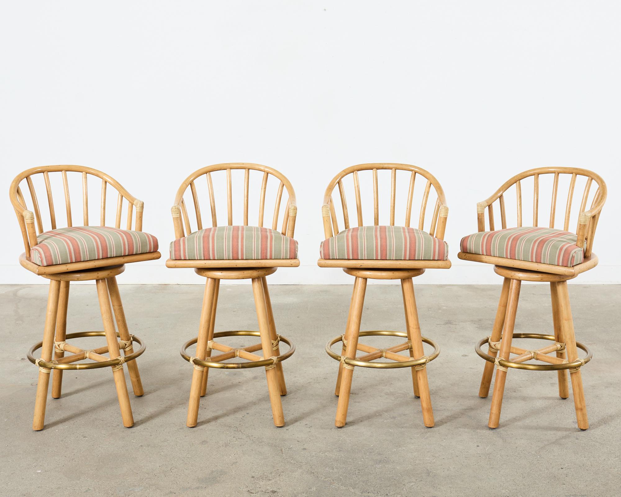 Gorgeous late 20th century set of four matching rattan and oak barstools made in the California organic modern coastal style by McGuire. The barstools feature a rattan swivel seat with a gracefully curved spindle back. The seat is upholstered with a