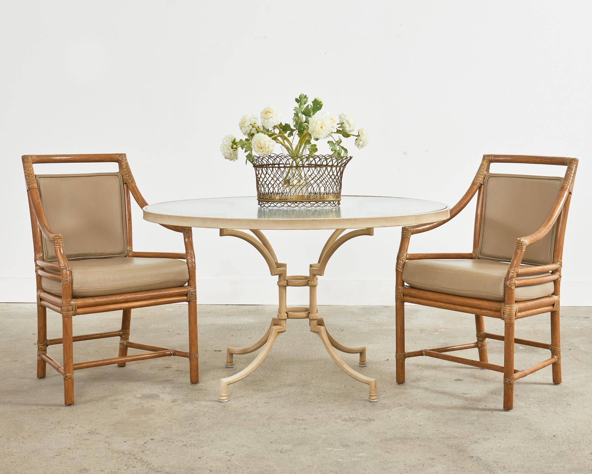 Bespoke set of four iconic rattan dining armchairs made in the California coastal organic modern style by McGuire San Francisco, CA. Model number MCM59B known as target chairs feature a square back with a target shaped splat. The inner circle of the