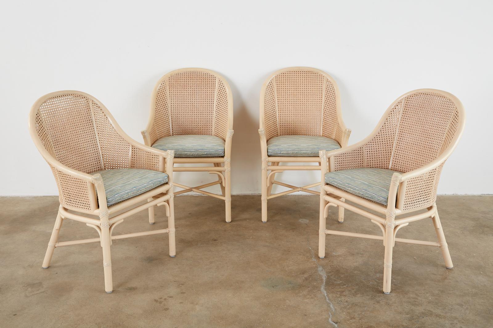 Iconic set of four genuine McGuire dining armchairs featuring double caned sides in a classic barrel form. Currently known as the Belden chair the vintage versions of these chairs were made to a higher quality standard. The newer chairs do not have