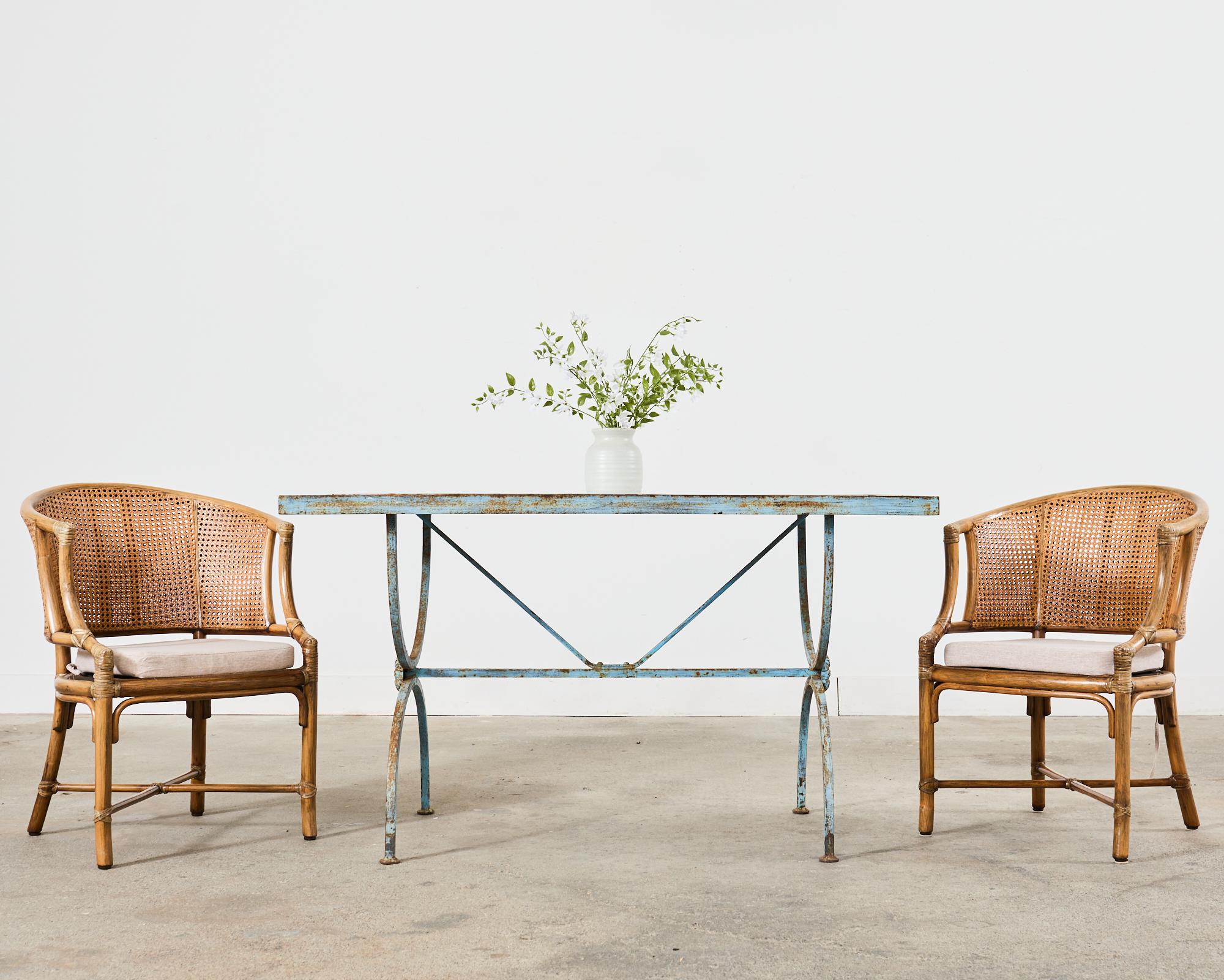 Gorgeous set of four rattan dining chairs made in the California coastal organic modern style by McGuire artisans. The chairs feature thick rattan pole frames with a barrel back form. The seat backs have a double-caned side construction with leather