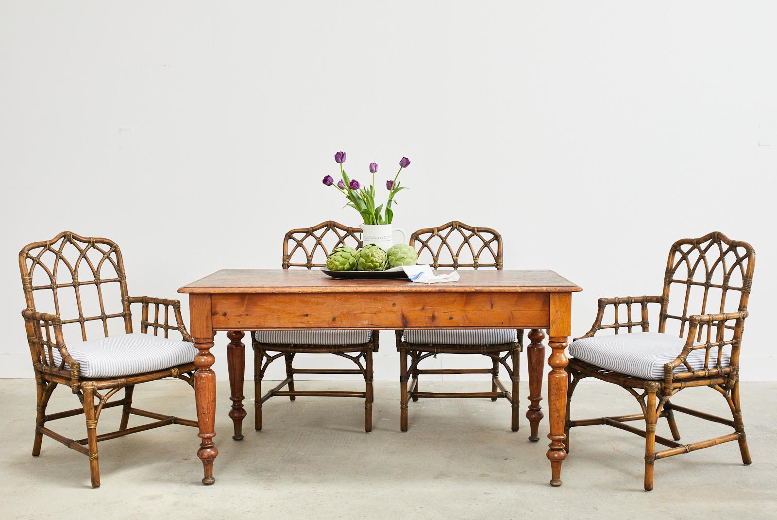 Handsome set of four genuine McGuire rattan dining armchairs featuring a cathedral back design. Crafted from thick rattan poles having a gothic lancet arch design and an open fretwork on the sides in a Chinese chippendale style. The exposed joints