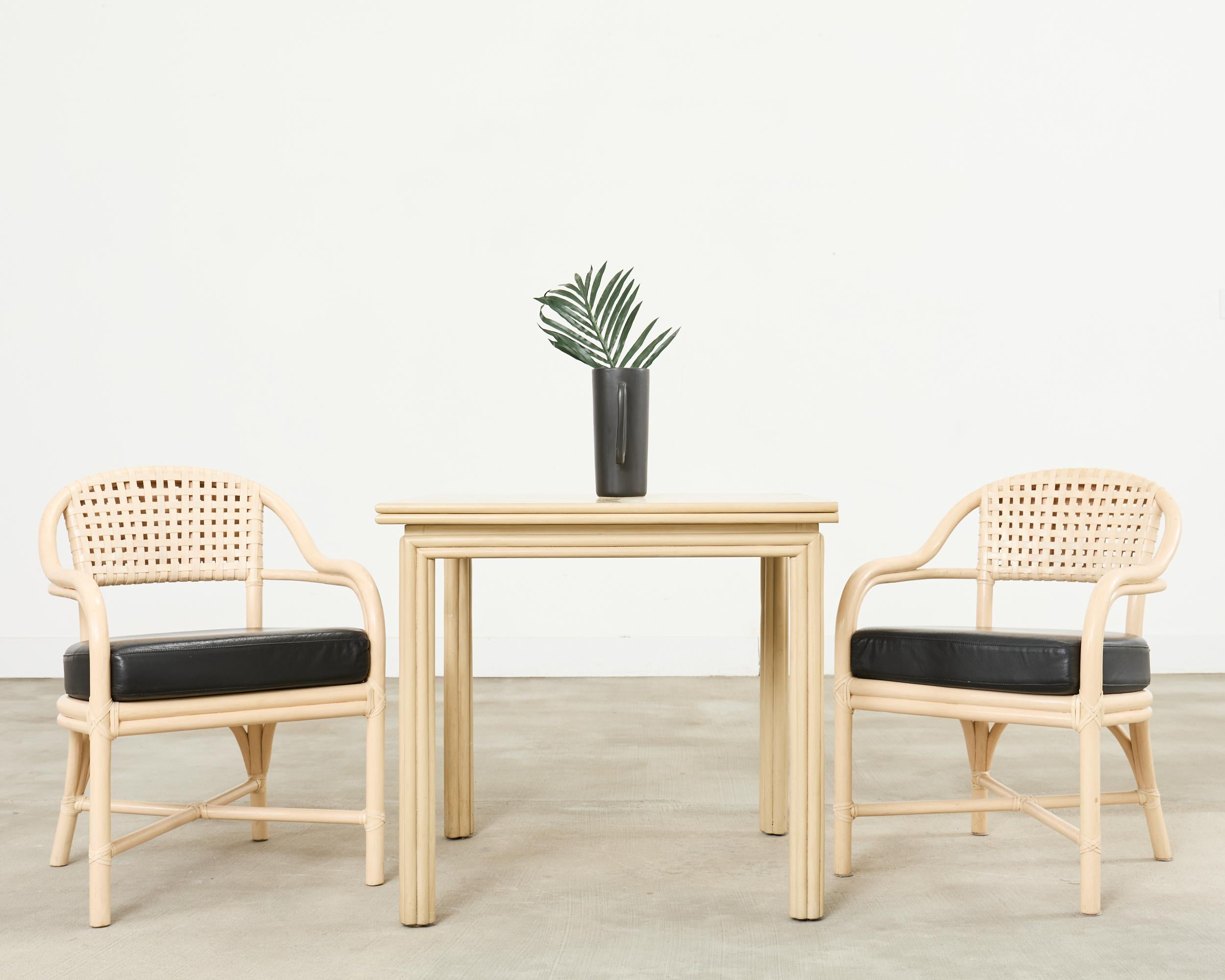 Iconic set of four McGuire barrel back design rattan dining armchairs made in the California coastal organic modern style. The chairs feature a woven laced rawhide back in geometric pattern. The seat has a fitted seat cushion with a black leather