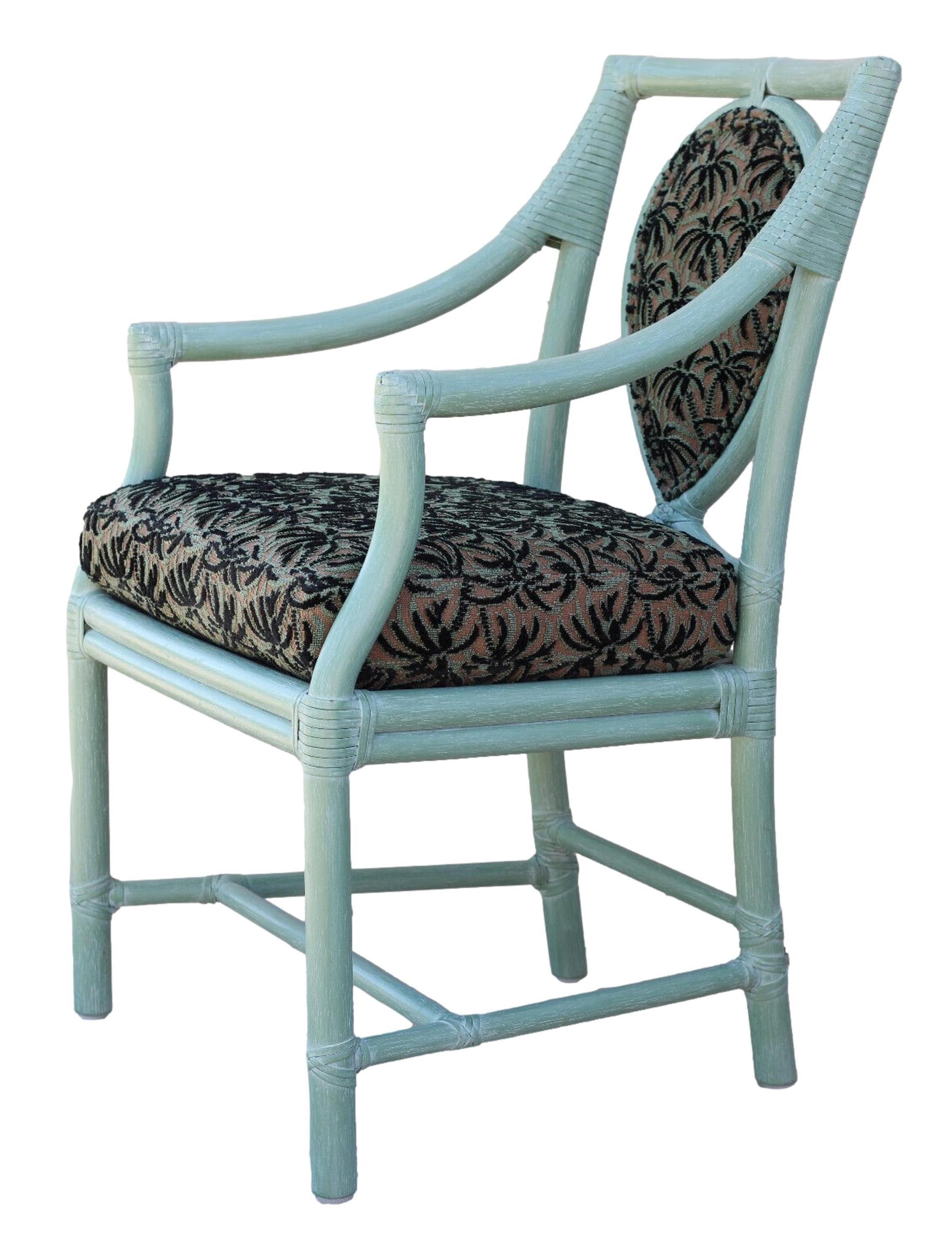 A set of four rattan arm chairs, designed by breakthrough innovator Elinor McGuire in the California organic modern style. These impeccably crafted dining chairs display a gestural loop framed within an open rattan back. Chairs feature gracefully