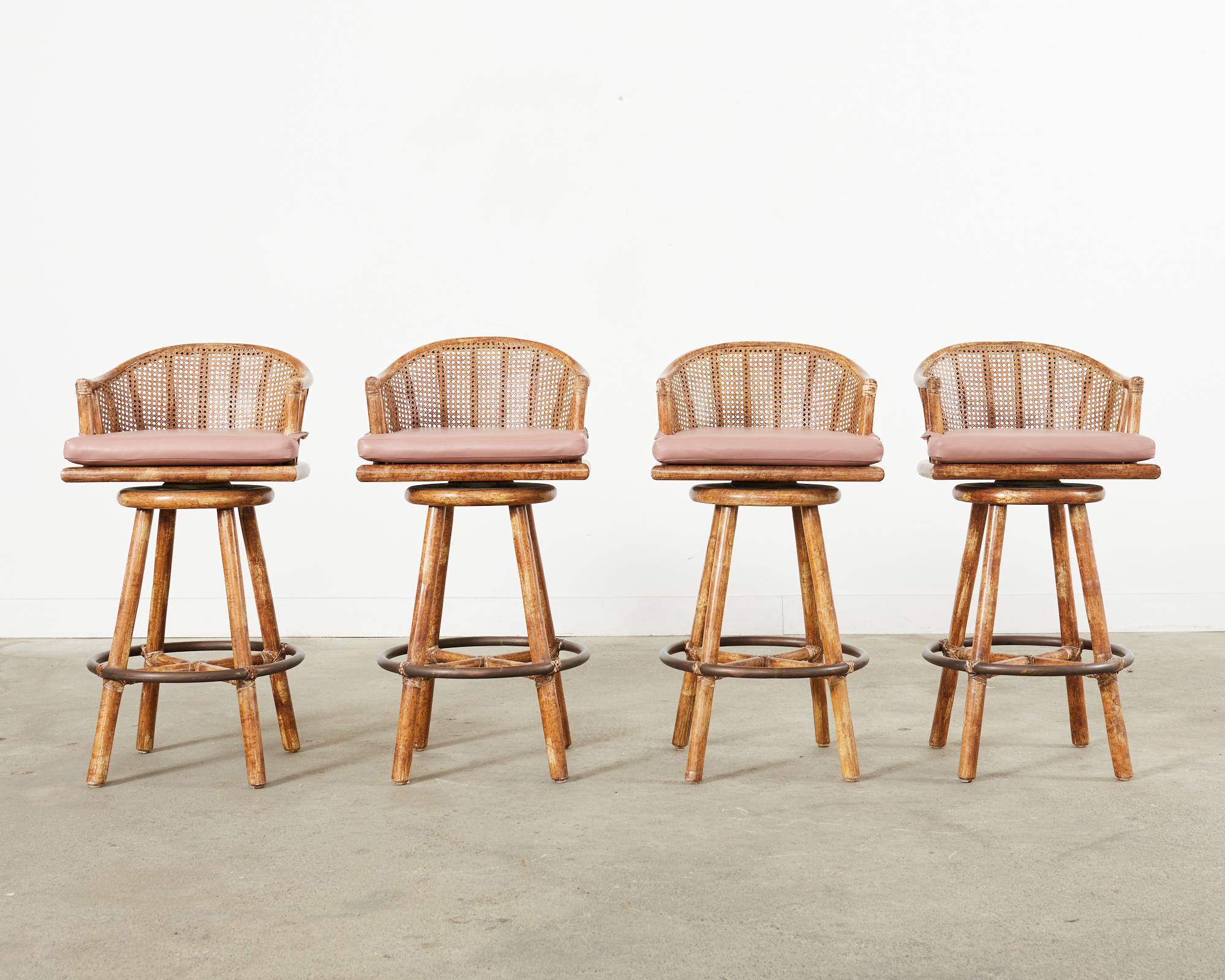Handsome set of four rattan and oak barstools made in the California coastal organic modern style by McGuire, San Francisco. The bar height stools feature a solid rattan and oak frame with a swivel seat. The generous seats have a gracefully curved