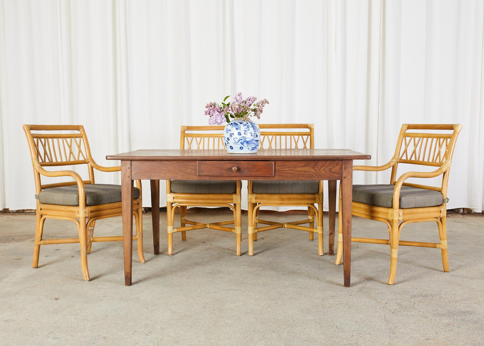 Impressive set of four bamboo rattan dining armchairs made in the manner and style of McGuire. The chairs have a square back with a faux rope twist top rail. The arms gracefully curve down to the generous seat topped with a loose seat cushion. The
