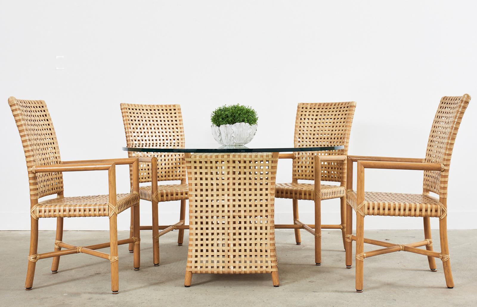 Rare set of four woven leather rawhide and rattan dining armchairs from McGuire's Antalya collection. Hand-crafted in the coastal California modern organic style featuring a thick rattan pole frame covered with a geometric pattern of woven lattice