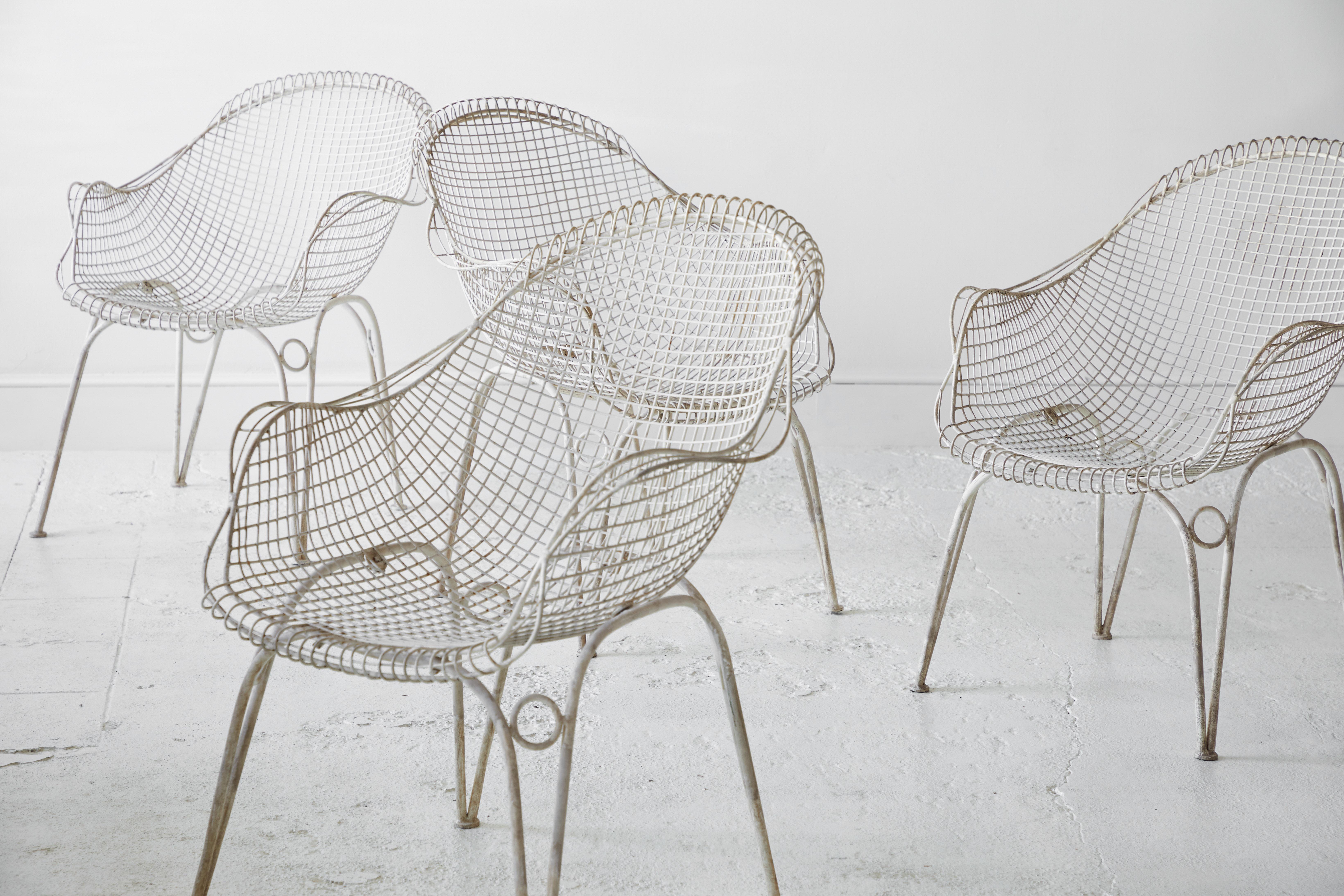 Set of four outdoor white painted metal mesh wire garden chairs. The chairs have a unique arching top. The chairs seat back in a very comfortable position.

 
