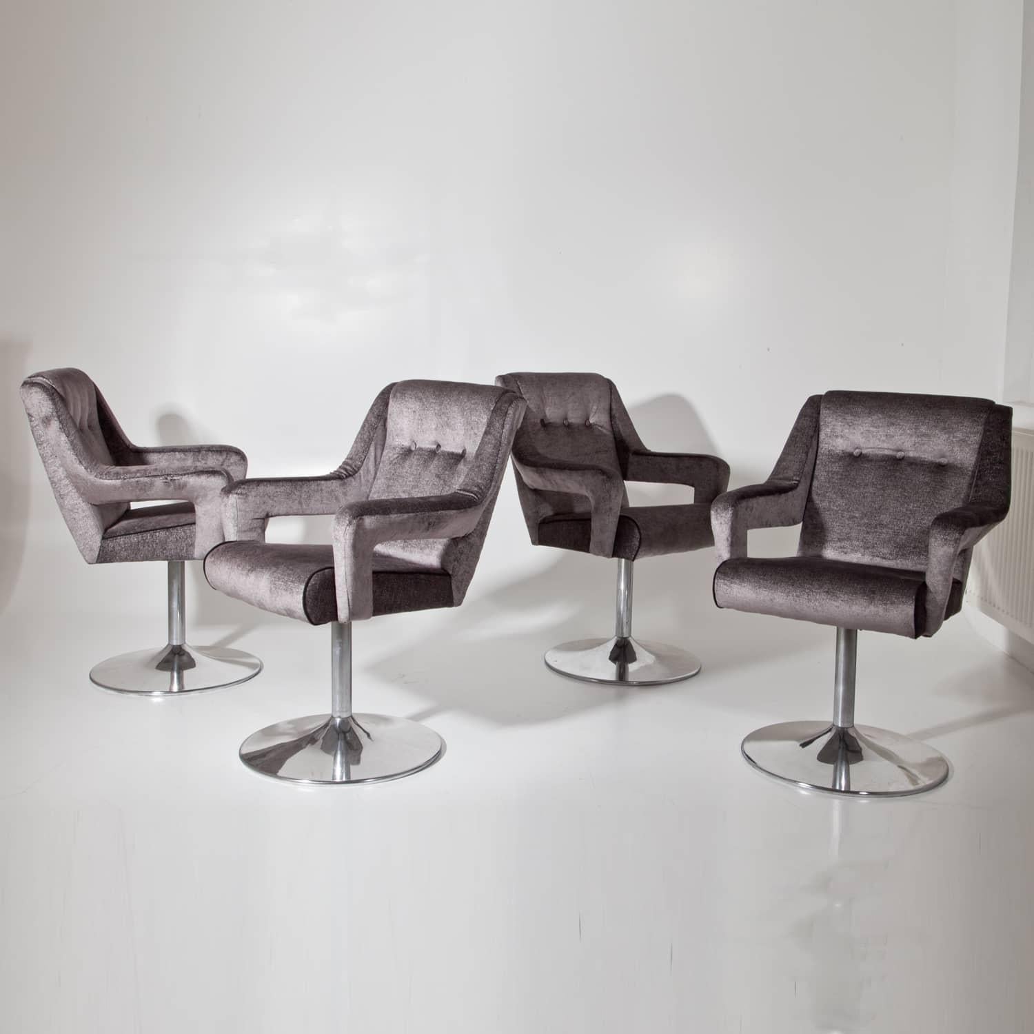 Set of four swivel chairs on round chromed legs and upholstered seats with armrests. The chairs were reupholstered with a high quality fabric in grey with silver-colored threads.