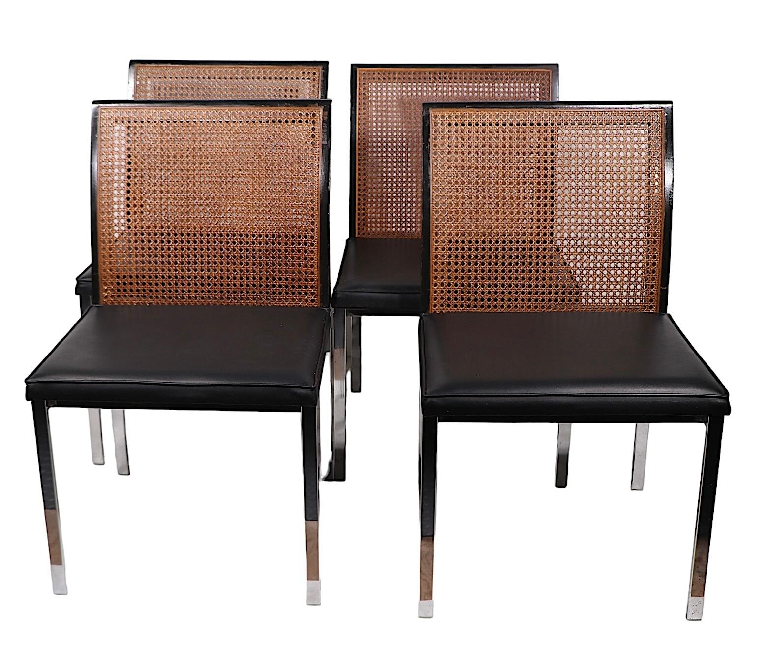 Voguish set of four chrome, black, and caned dining chairs designed by Paul McCobb for Lane Alta Vista, circa 1960/70's. These rare chairs feature squared chrome bar frames, with black lacquered and caned backs, and original black vinyl seat