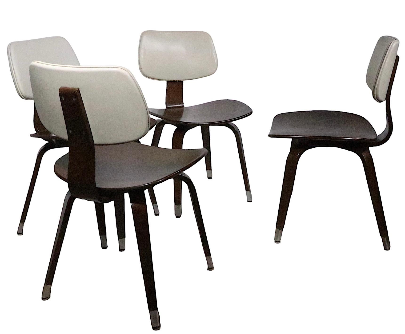 Chic set of four dining chairs, made in the USA, circa 1950's ,  manufactured by Thonet. The chairs are constructed of  bent plywood, vinyl and aluminum, they are currently in a  later, but not new, dark brown finish, with creme colored vinyl 