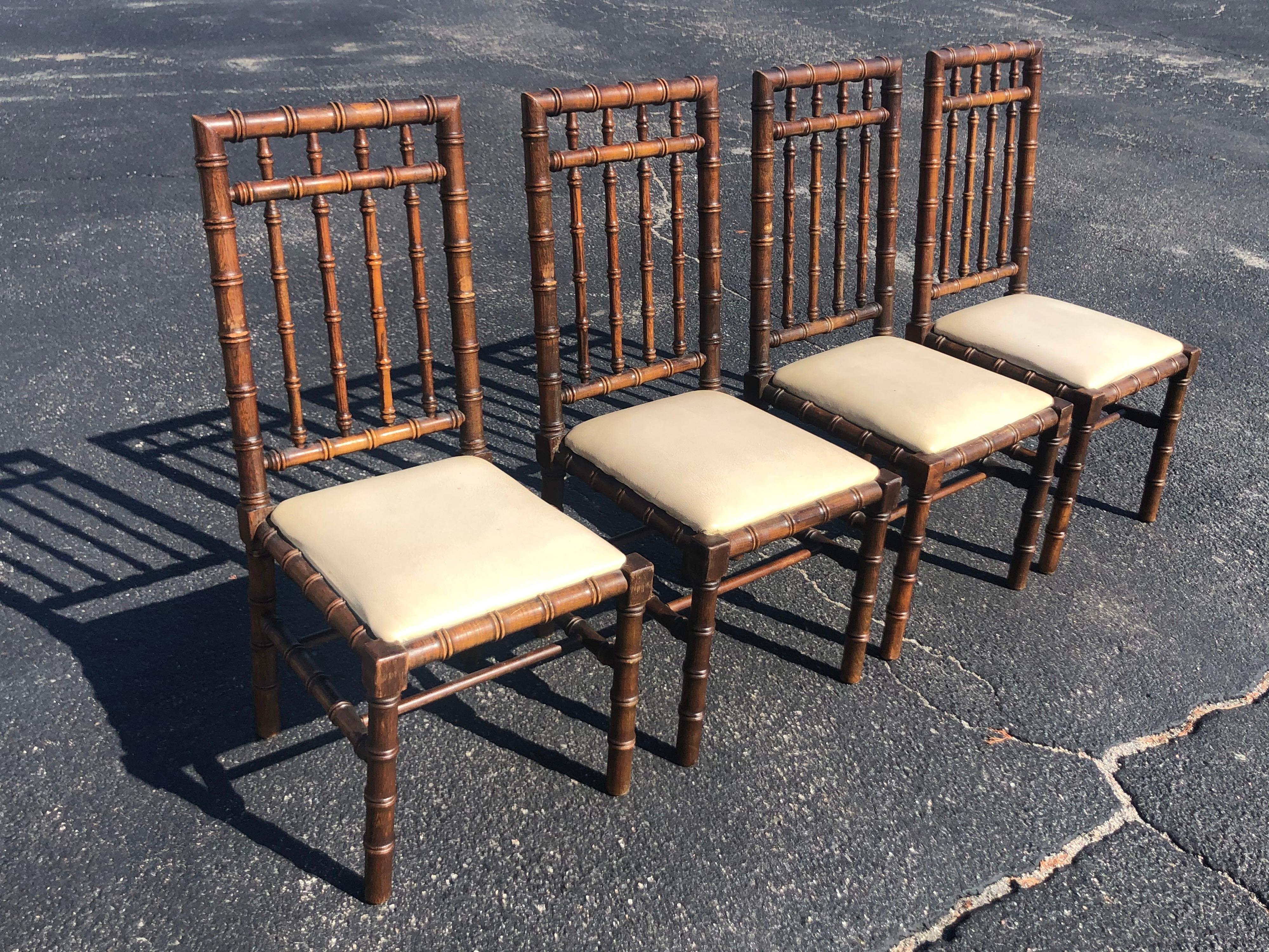 Set of four Mid Century faux bamboo chairs. These highly detailed carved chairs are made of solid oak wood. They have an off-white vinyl seat pad. Also available are a matching dining table and credenza. This whole set would look great with a high