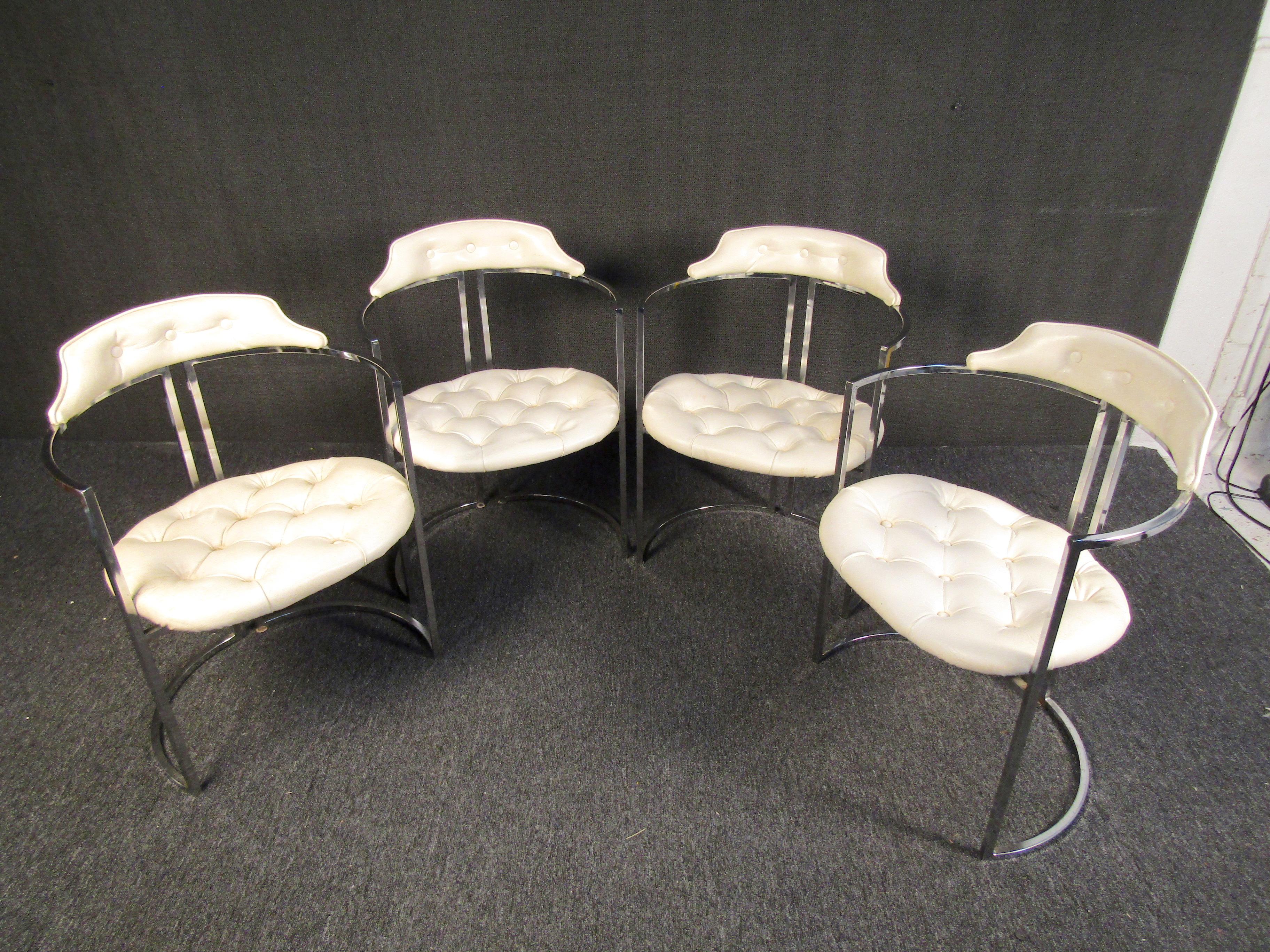 A set of four impressive Mid-Century Modern chairs styled after the designs of Milo Baughman. Curved backs and a circular base give these chairs an interesting geometric form that is complemented by white leather cushions and chrome. Please confirm