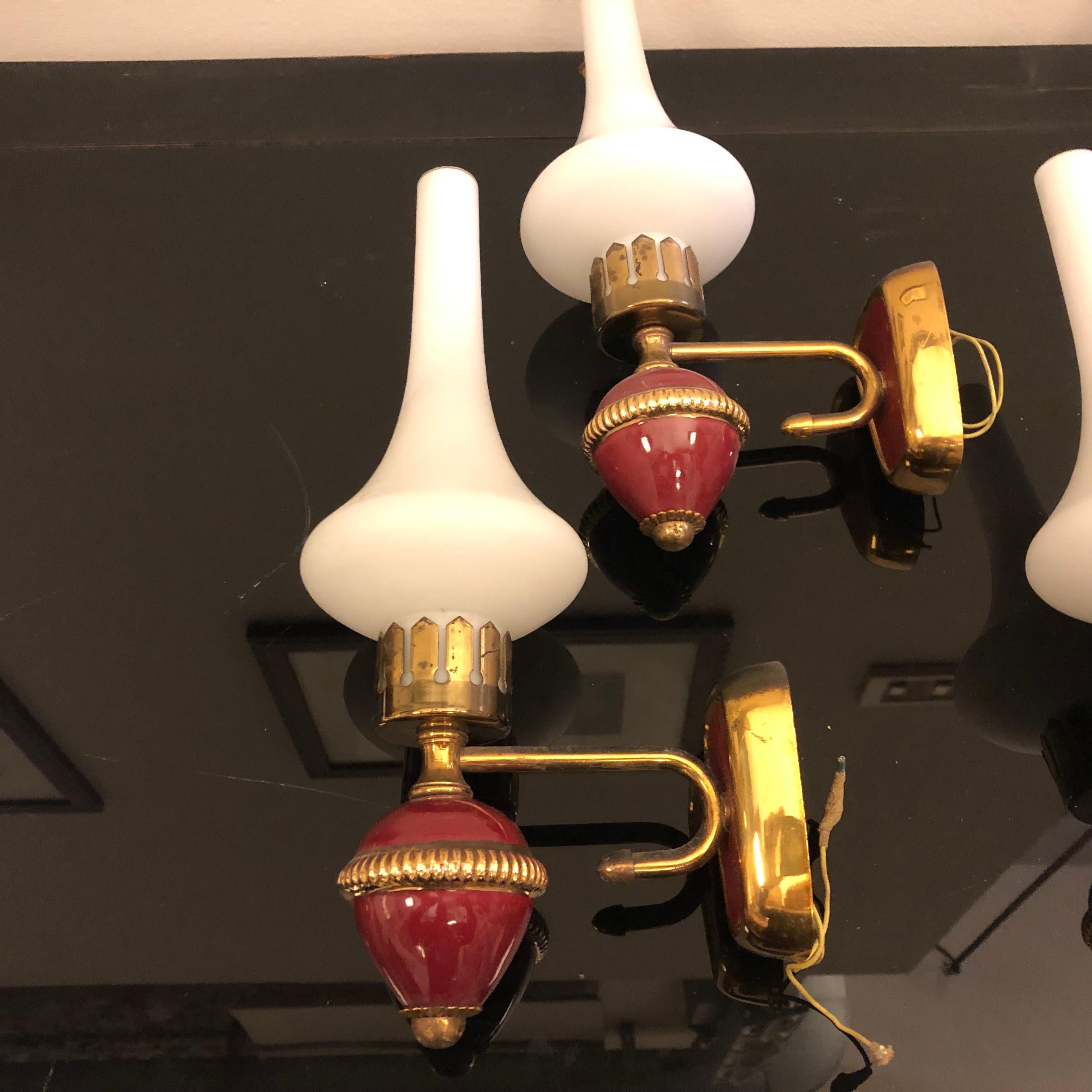 A particular set of four red painted brass and white satin glass wall sconces. They work both 110-240 volts and need regular e14 bulbs. Brass is in original patina the create a vibrant vintage look.