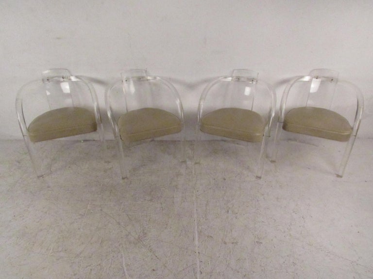 This stunning pair of vintage modern dining chairs feature a tubular Lucite frame with arched arm rests. A unique curved backrest and thick padded seating covered in vinyl ensures maximum comfort. This unusual set of midcentury dining chairs make