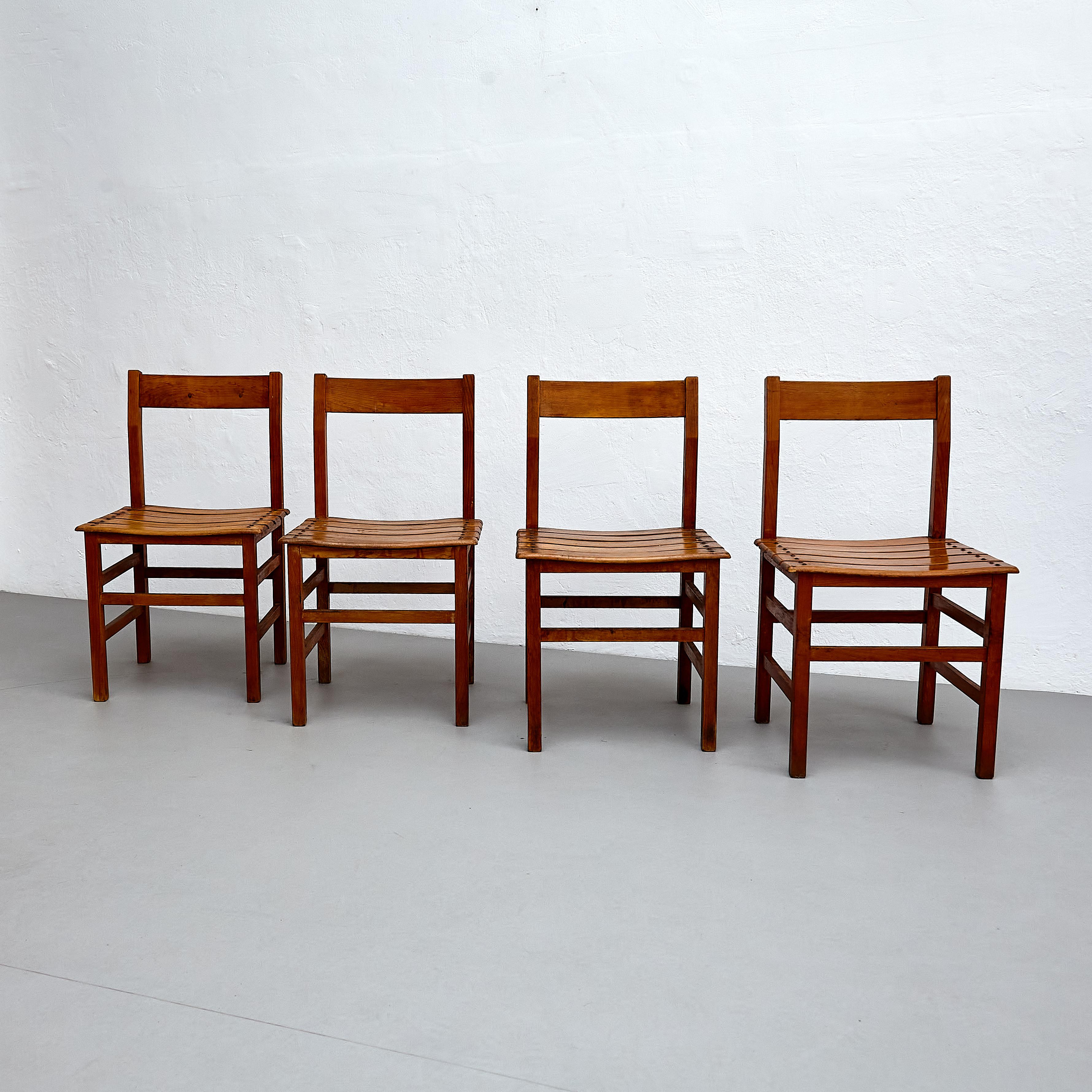Set of four rustic wood French chairs.

Embrace the rustic charm of this set of four mid-century modern rationalist wood chairs, manufactured in France circa 1960. These chairs showcase a timeless design, making them a perfect addition to any home