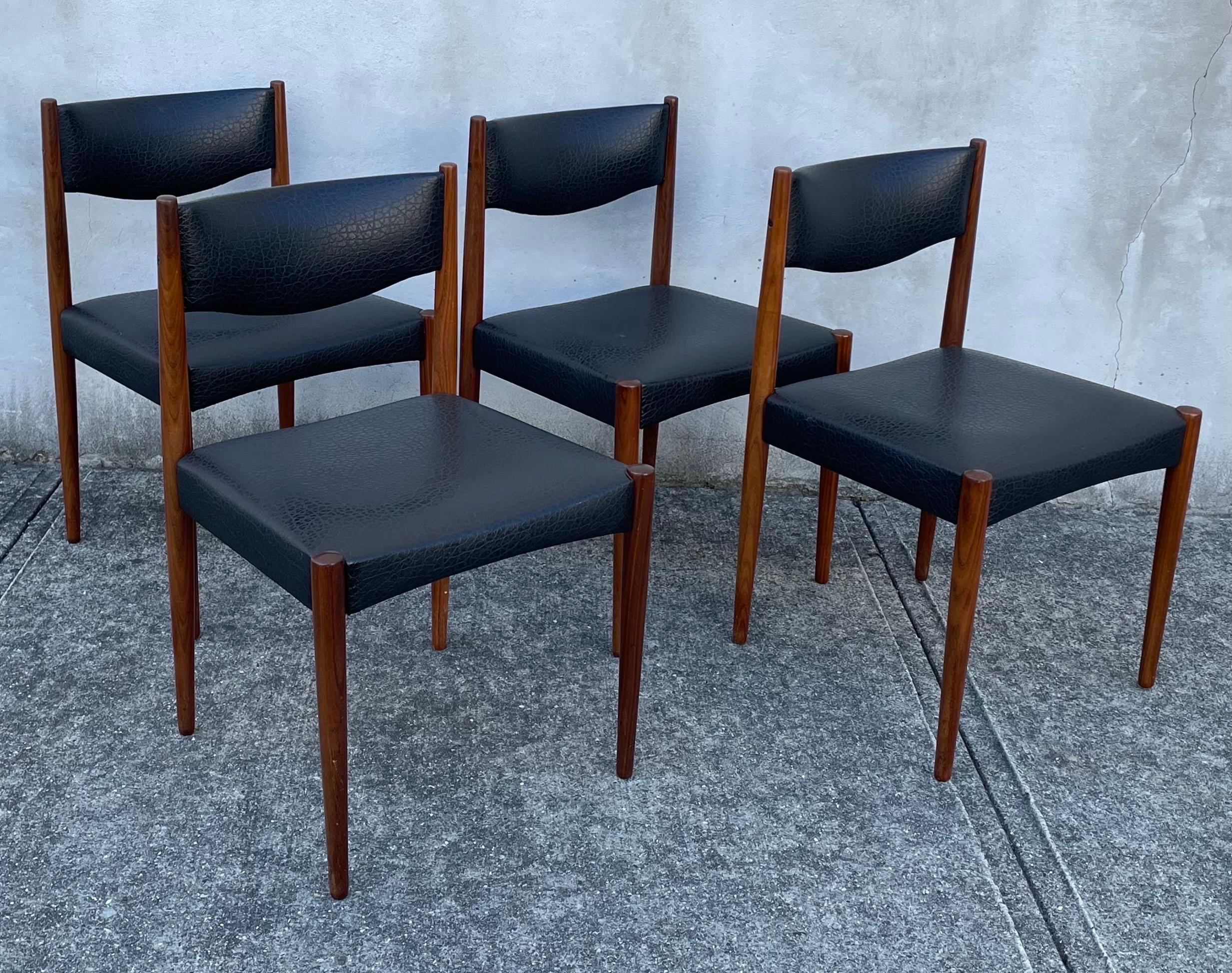 Beautiful set of four teak dining chairs with faux black leather seats. All original and authentic Mid Century Modern and very much in the style of Aksel Bender Madsen, made in Holland, 1960's.