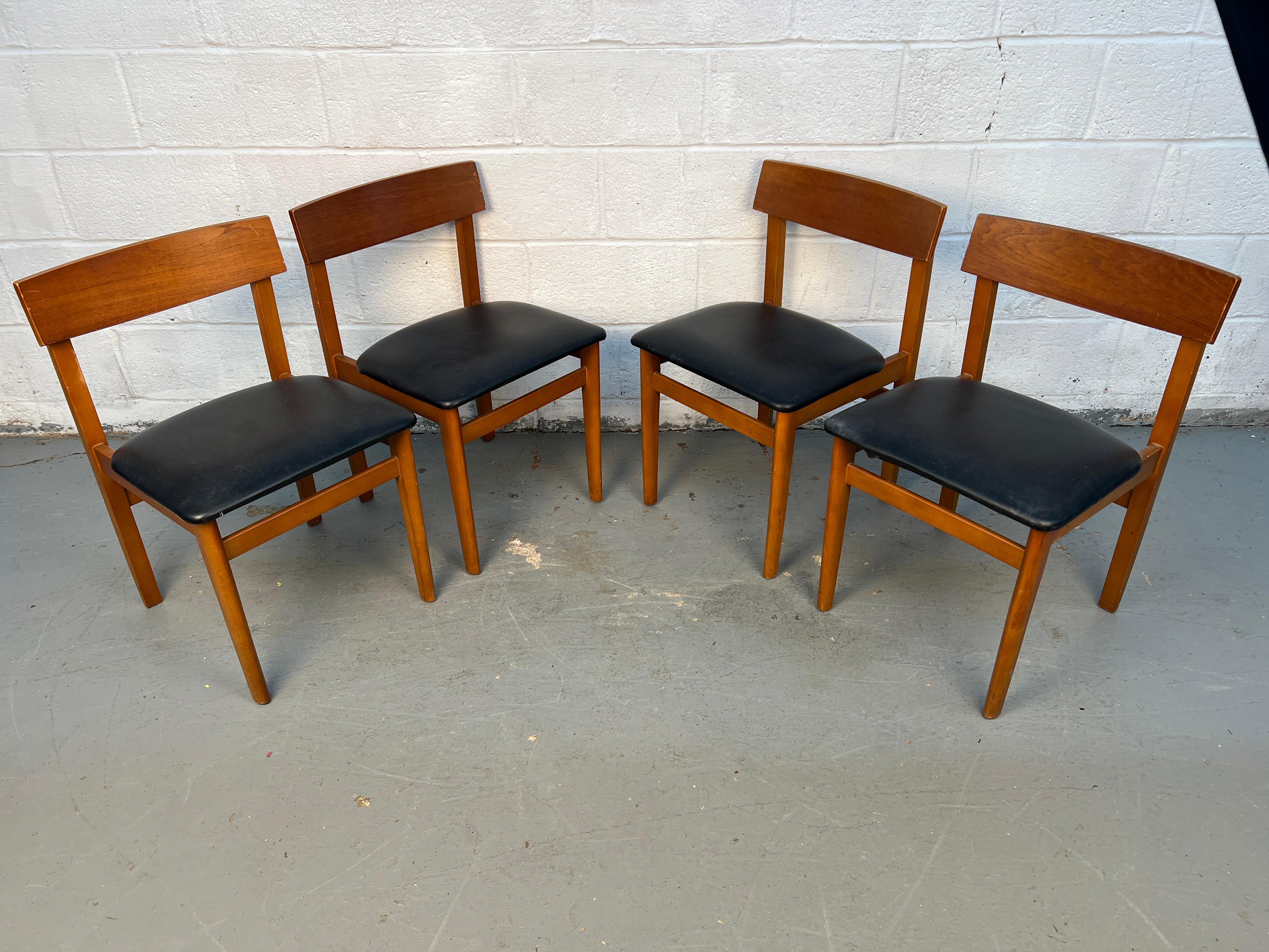 Elegante set di quattro sedie da pranzo moderne di metà secolo realizzate in teak e abbinate a eleganti cuscini in pelle nera. Caratterizzati da linee scandinave pulite e comode sedute, donano un calore e uno stile senza tempo a qualsiasi spazio da