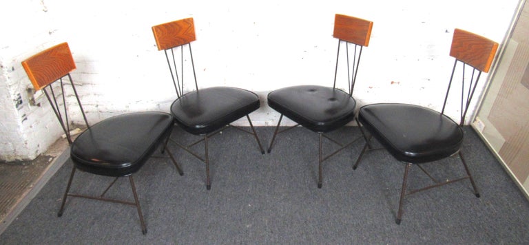 Unique set of four vintage modern dining chairs. These chairs feature vinyl cushioned seats, with deeply grained wood back rests and a slender metal frame. Perfect for any dining area.

Please confirm item location (NY or NJ).