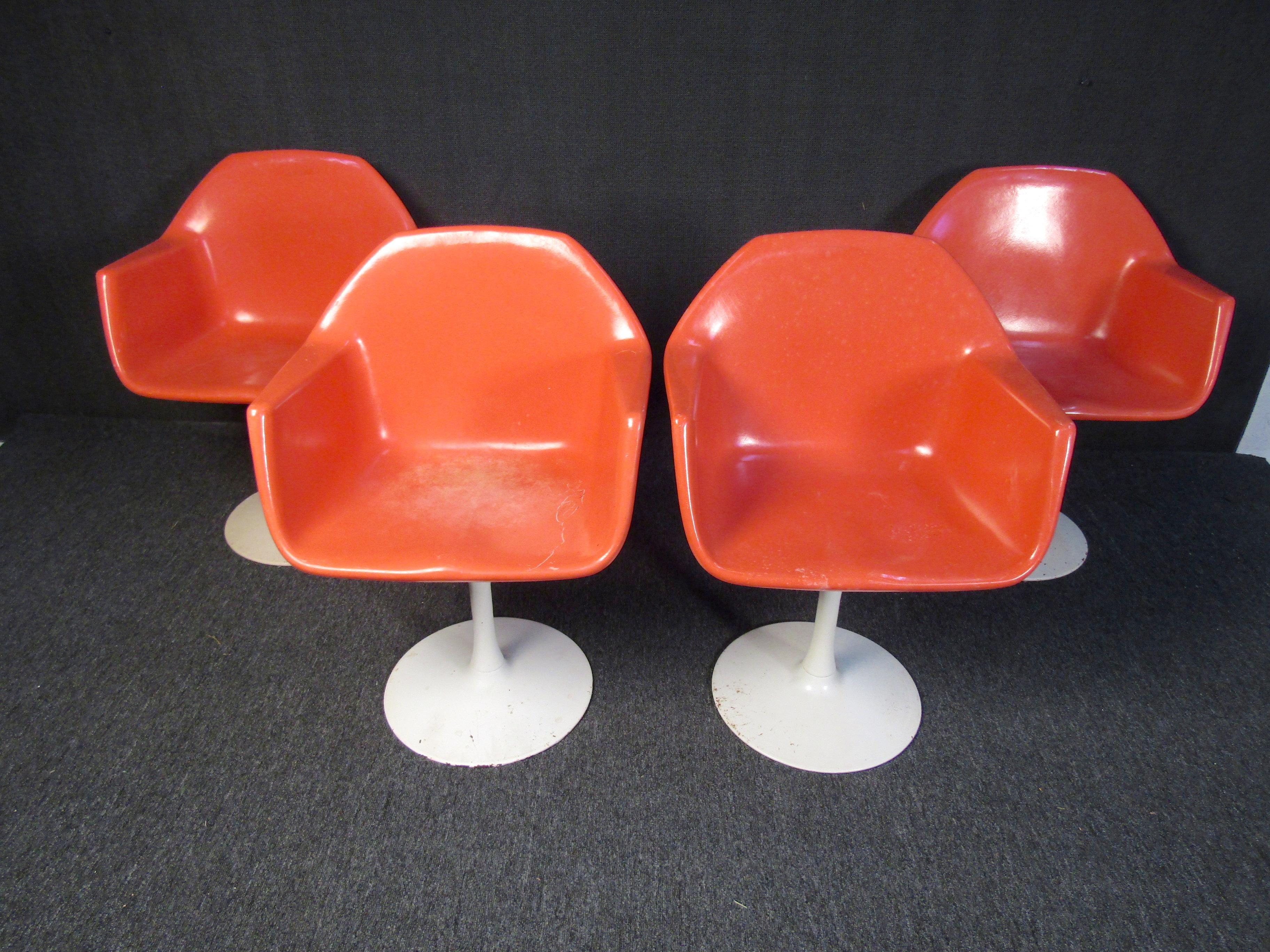 A set of four tulip chairs that pop with Mid-Century Modern style and a bright peach color. A comfortable design sits upon white pedestal bases, making these chairs a unique and stylish addition to any setting. Please confirm item location with
