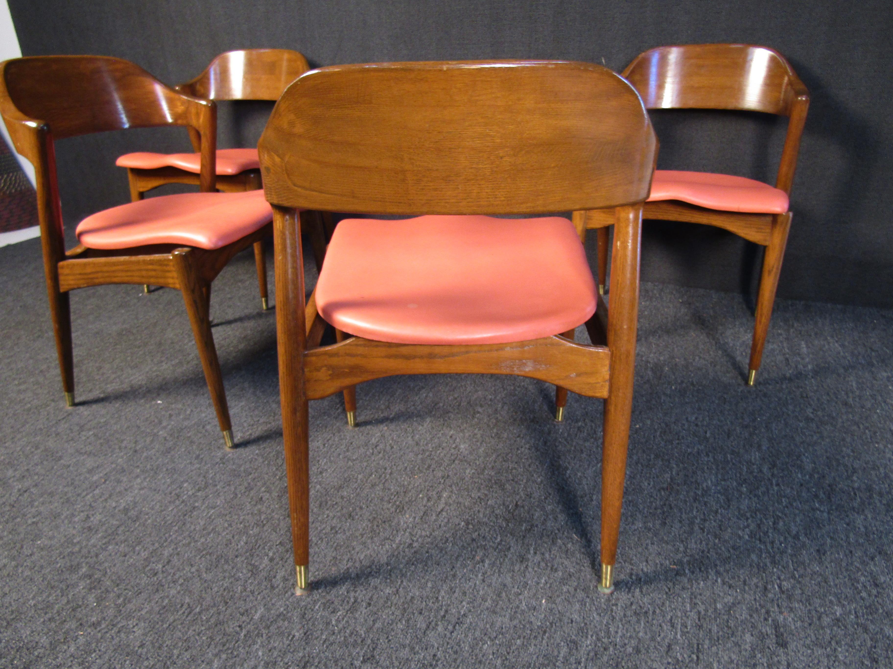 These striking Mid-Century Modern chairs combine an elegant walnut frame with salmon seats and brass footing on the chair legs. Perfect for any dining room or home setting, these chairs are full of sturdy quality and vintage style. Please confirm