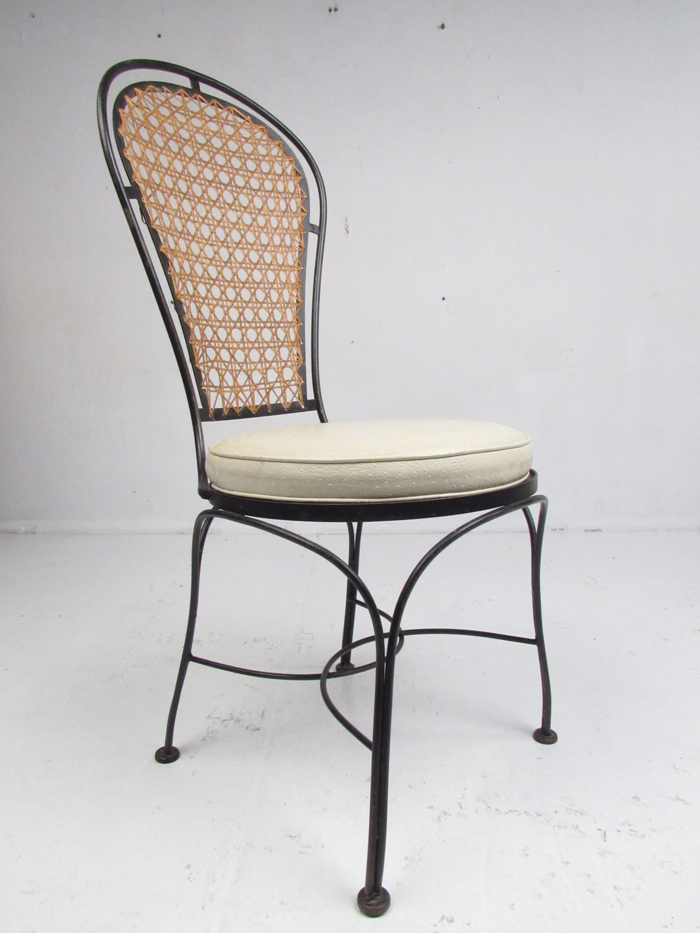 This stunning set of four vintage modern dining chairs boast sculptural wrought iron frames with thick padded seats and a woven cane back rest. A sleek and comfortable design that looks great on the patio or in the dining room. The bent rod iron