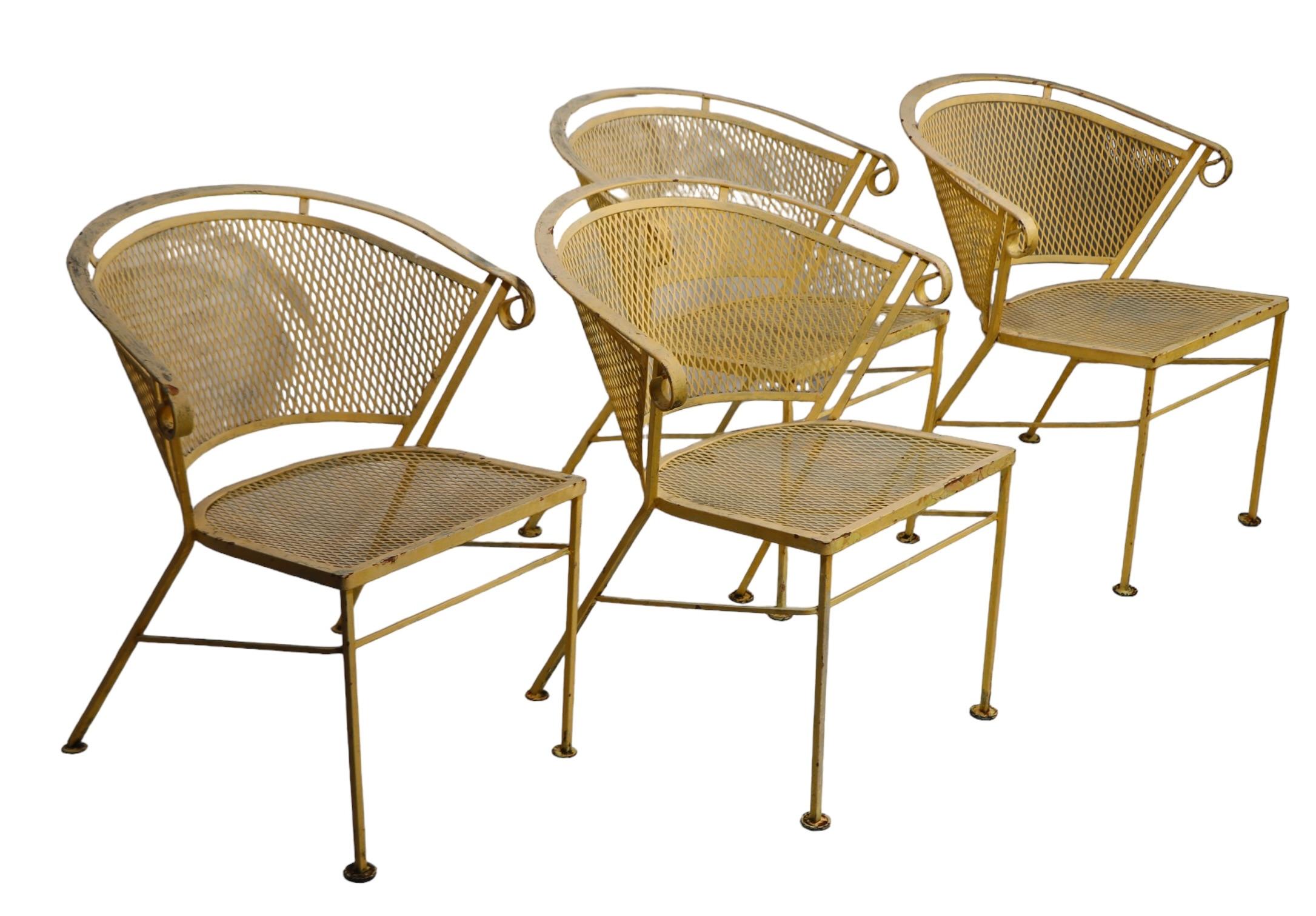 Set of four Mid Century garden, patio, poolside dining chairs, made by the Woodard Furniture Company, circa 1950/60's. The chairs are all structurally sound and sturdy, they are currently in later, but not new, yellow paint surface. Please view our