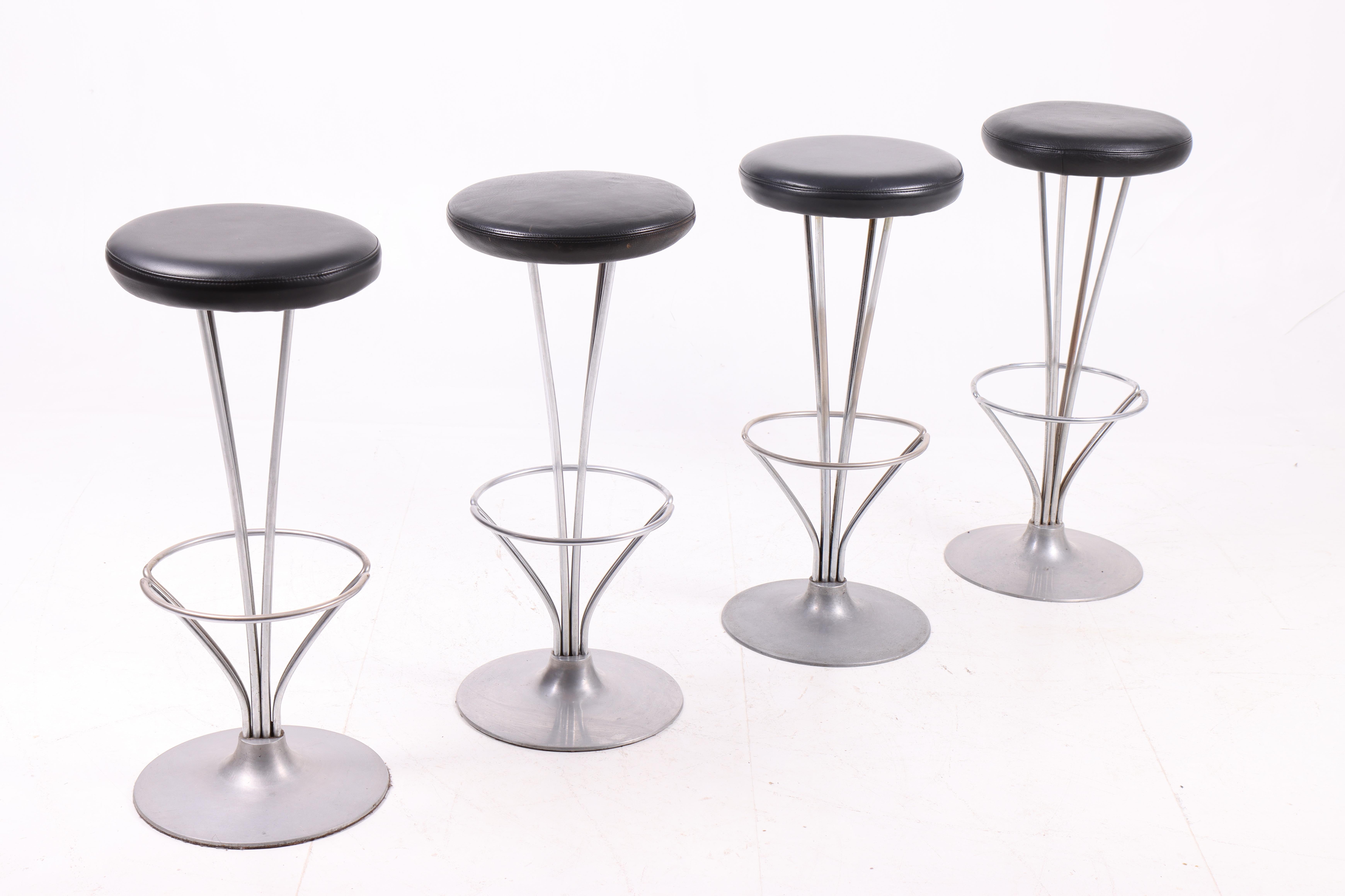 Set di quattro sgabelli alti in metallo con sedute in pelle patinata. Disegnato da Piet Hein per Fritz Hansen. Prodotto in Danimarca, in ottime condizioni. Ideale per la cucina o per un bar.
