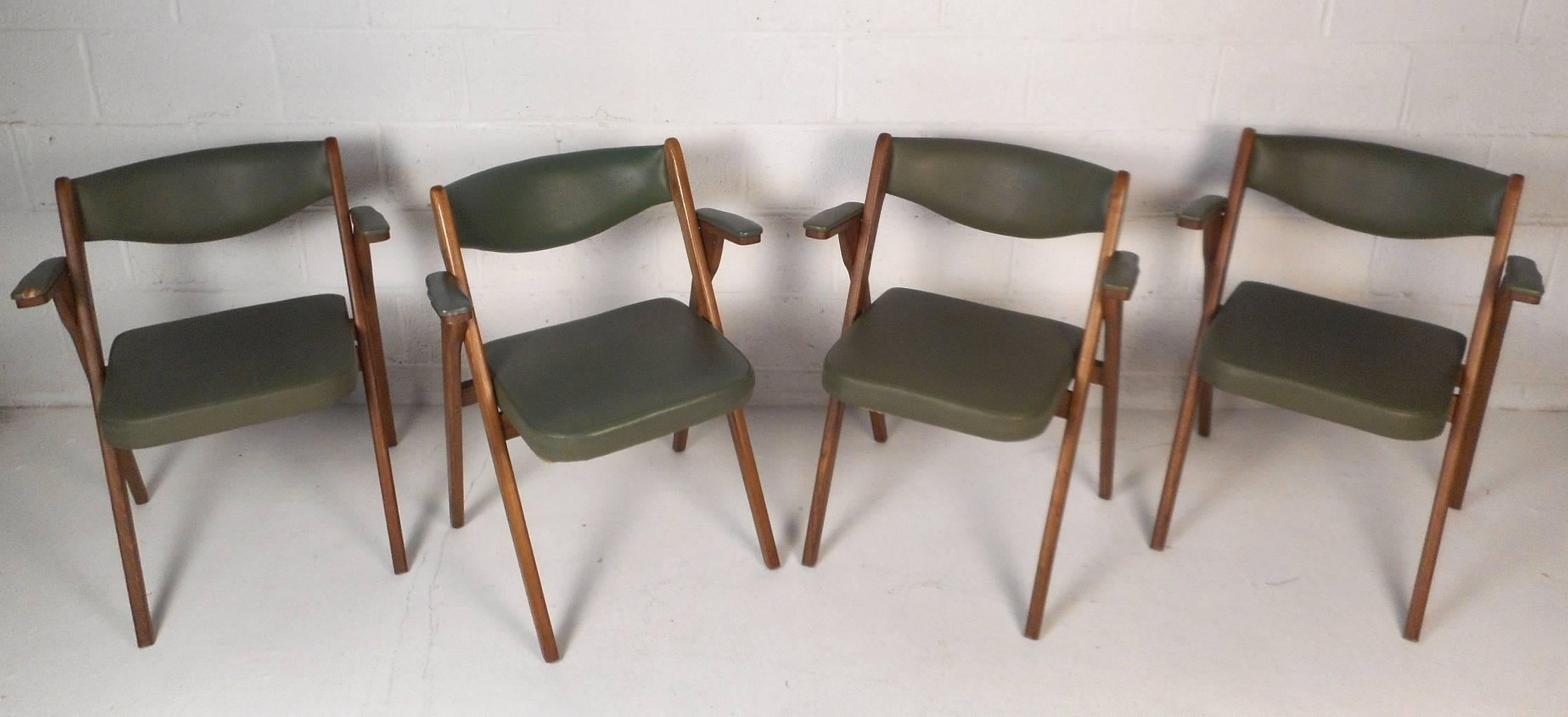 This beautiful set of four vintage modern chairs feature an angled walnut frame that conveniently folds up for storage. A unique curved back rest, padded arm rests, and a sturdy walnut frame show quality craftsmanship. The thick padded seat and back