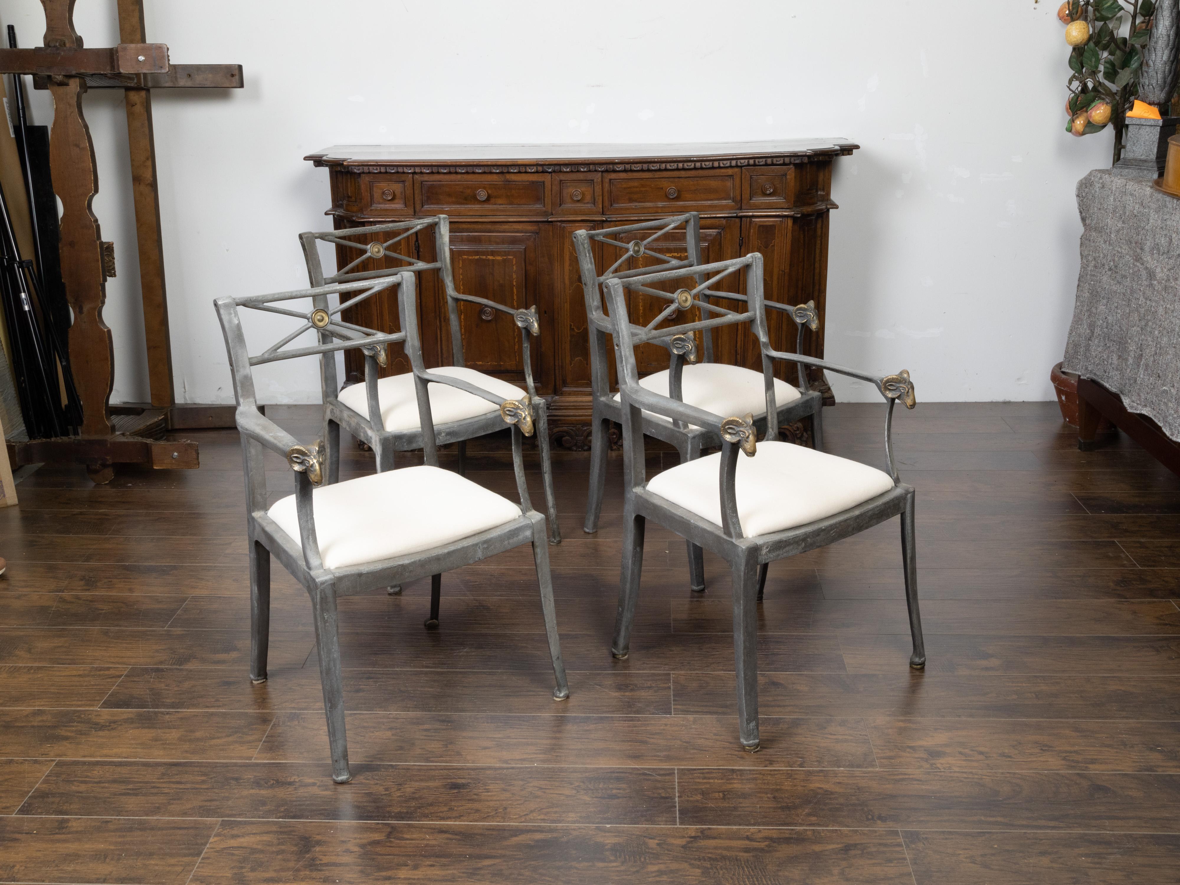 A set of four vintage Italian metal armchairs from the mid 20th century, with brass rams' heads and new upholstery. Created in Italy during the midcentury period, each of this set of four armchairs features a pierced back with X-form motifs accented