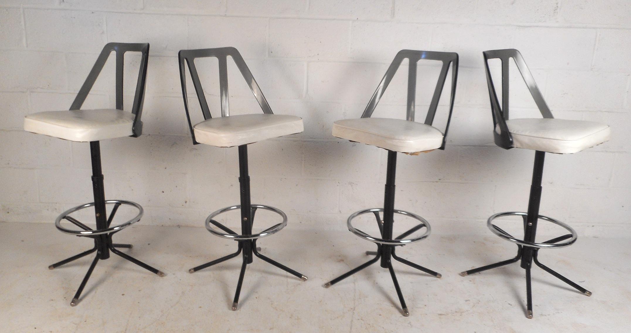 This beautiful set of four vintage modern bar stools feature unique tinted Lucite back rests and white vinyl upholstery. A comfortable design with the ability to swivel and a conveniently placed circular kick rest. A sleek design with a sturdy metal