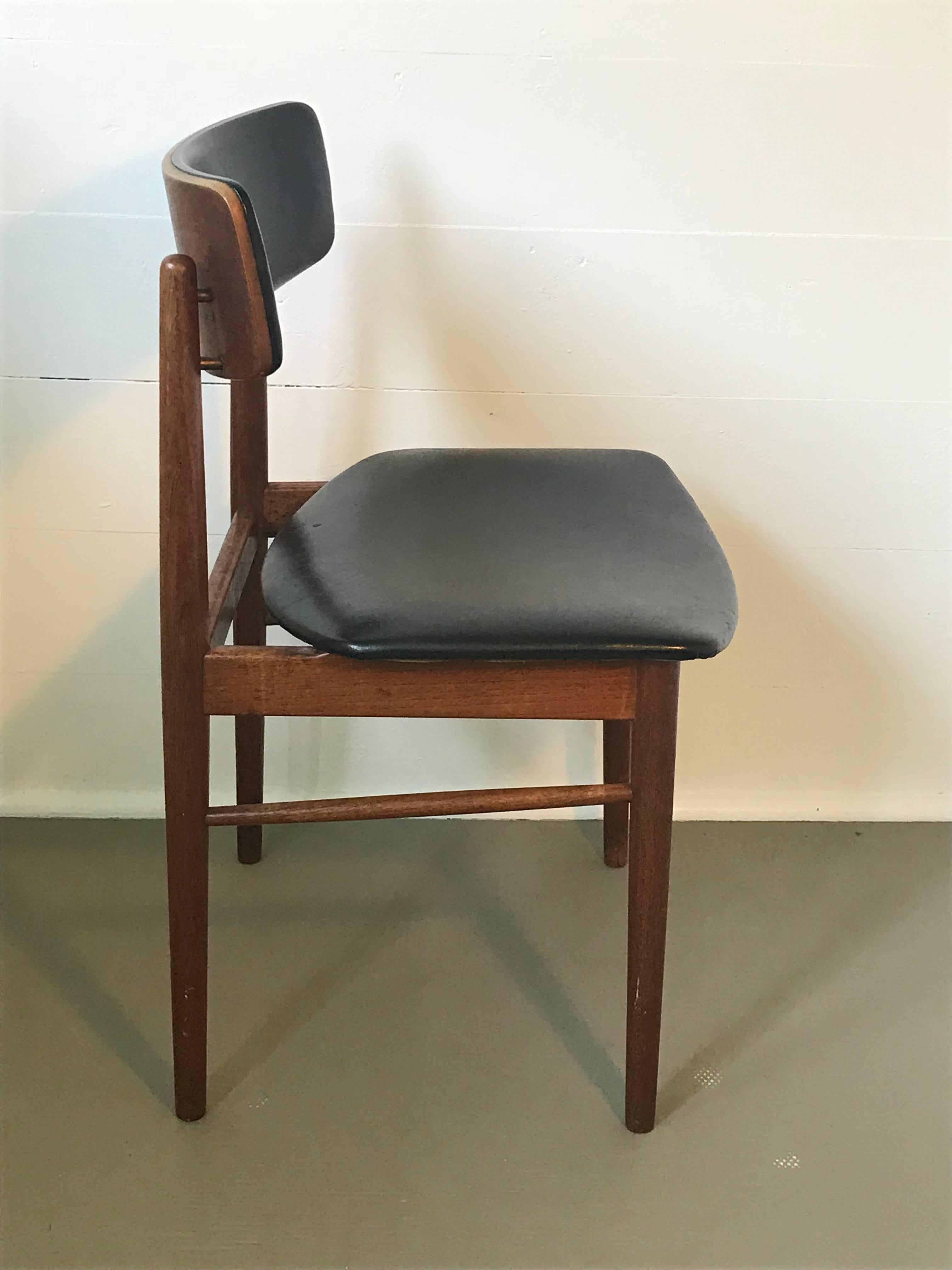 Nice set of four Mid-Century Modern teak dining chairs with original black vinyl seats and backrest, similar to the designs of Arne Vodder, Denmark. The chairs are structurally sound and in good condition for their age and use, vinyl in good