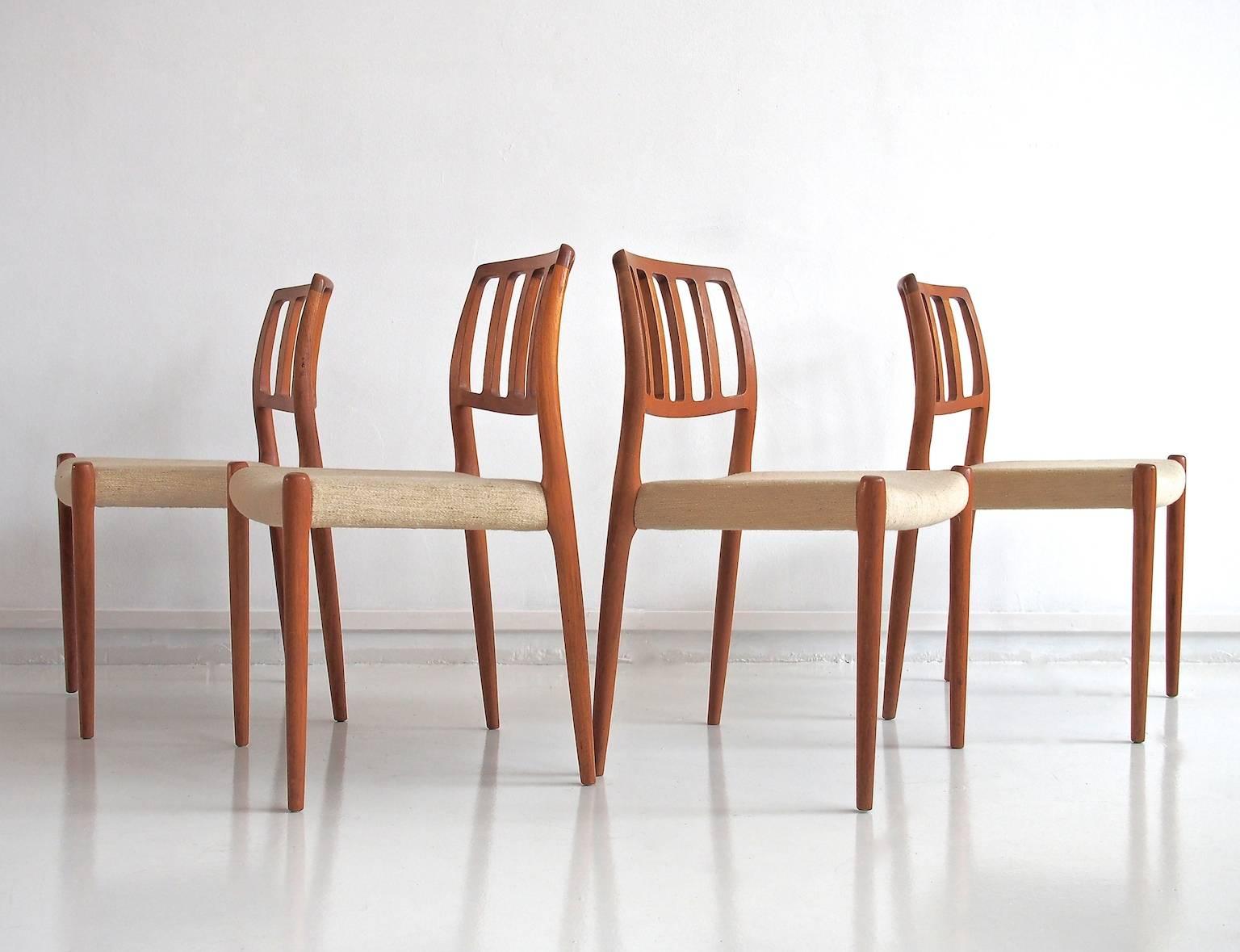 Four dining chairs, model 83, designed by Niels O. Møller in 1974. Organic design of solid wood. Seats with light beige mottled wool fabric. Manufacturer stamp underneath.