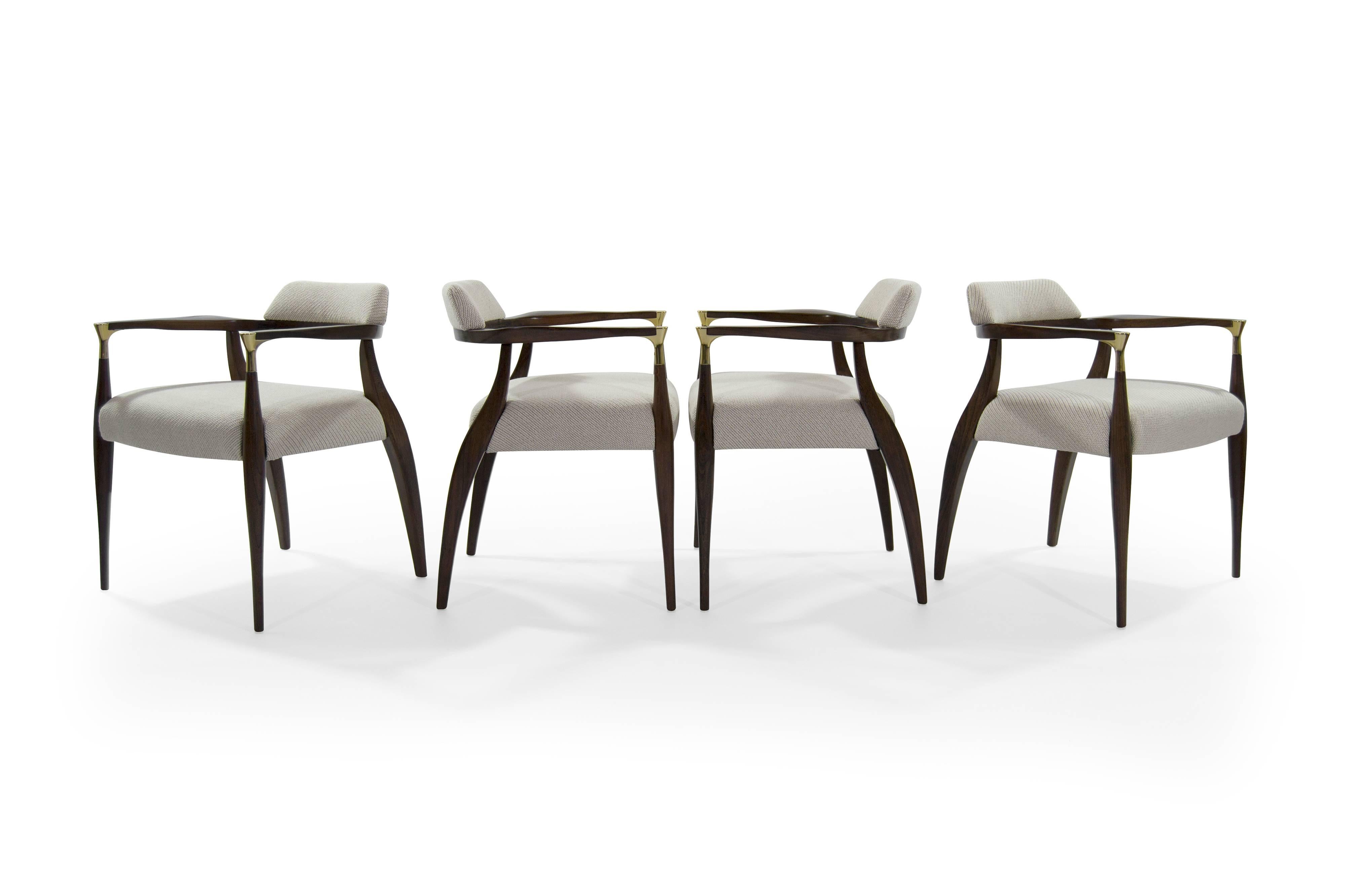 Four modern armchairs in the style of Ib Kofod-Larsen, circa 1950s.

This set features newly polished brass arm-tip details. Newly upholstered in an off-white coda wool by Maharam/Kvadrat. Sculptural walnut frames fully restored.
