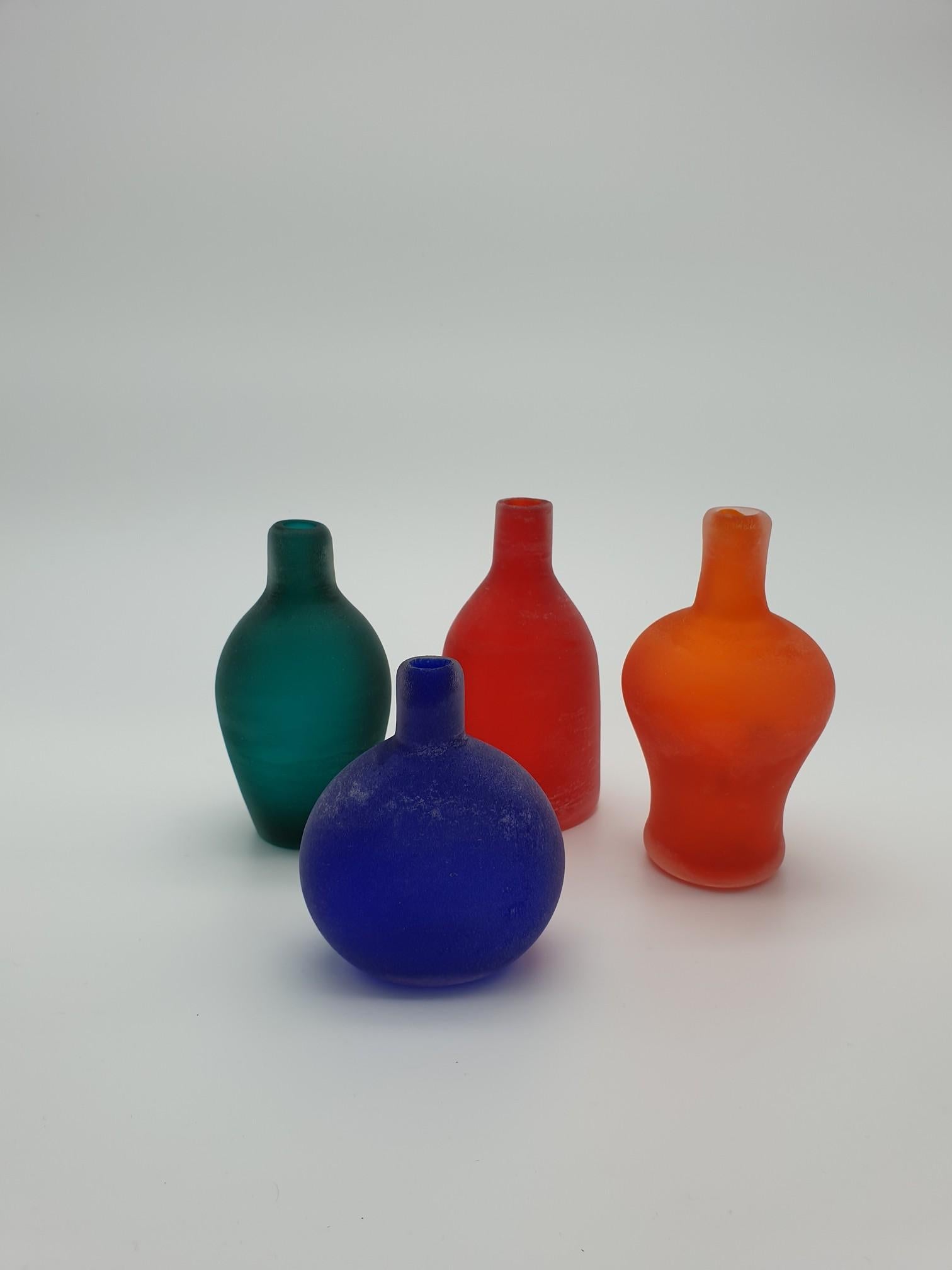 Set of bright colored Murano glass small vases, completely handmade in the mid-1980s by the historical Gino Cenedese e Figlio glass-factory. The four small vases are of assorted shapes and colors: a round-shaped blue vase, a spindle-shaped green
