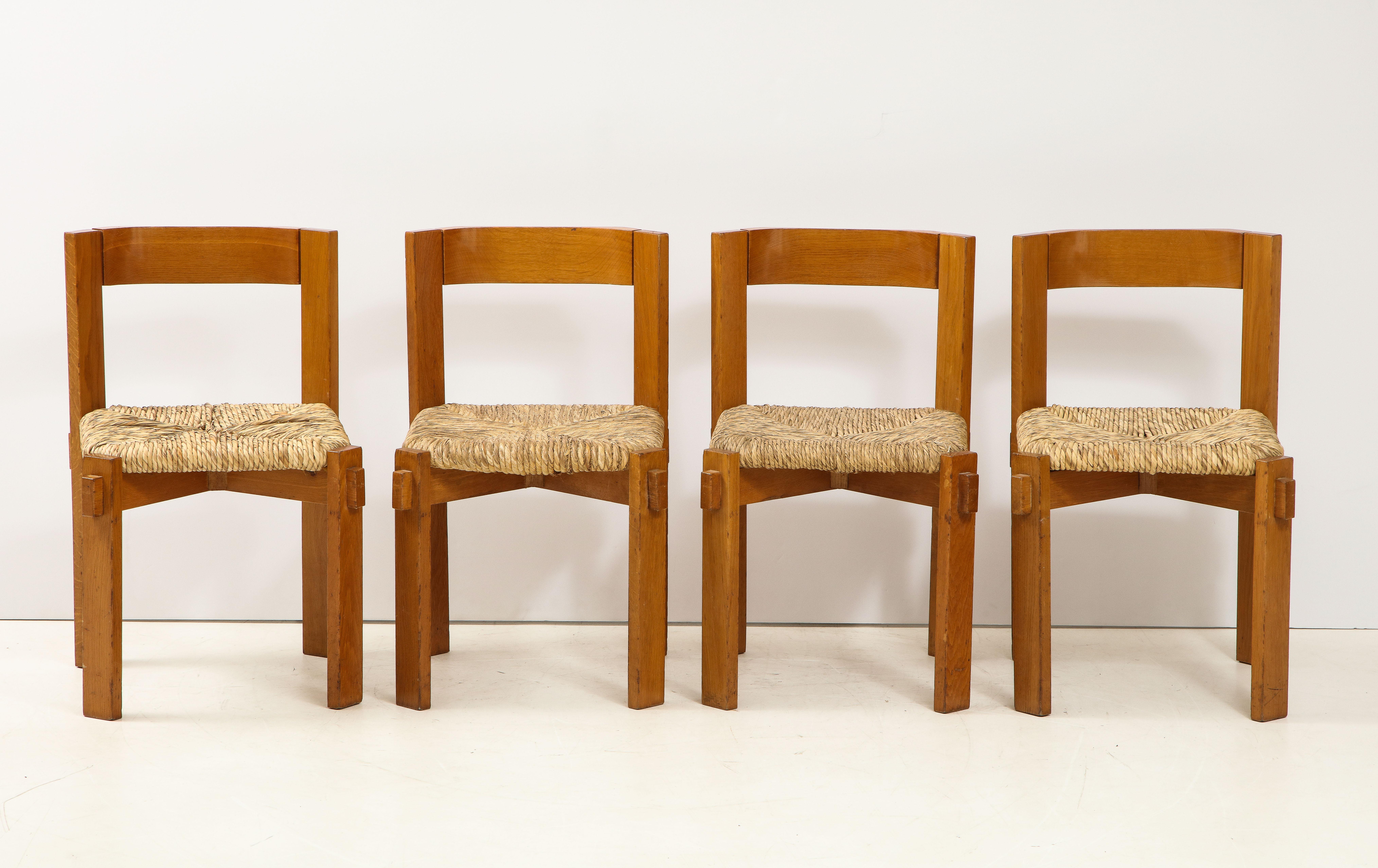 A set of four modernist Italian oak and straw chairs, the oak a beautiful soft color complements the organic material of the straw seats, which are removable. The curved back, angled legs and interlocking wood construction is a wonderful example of