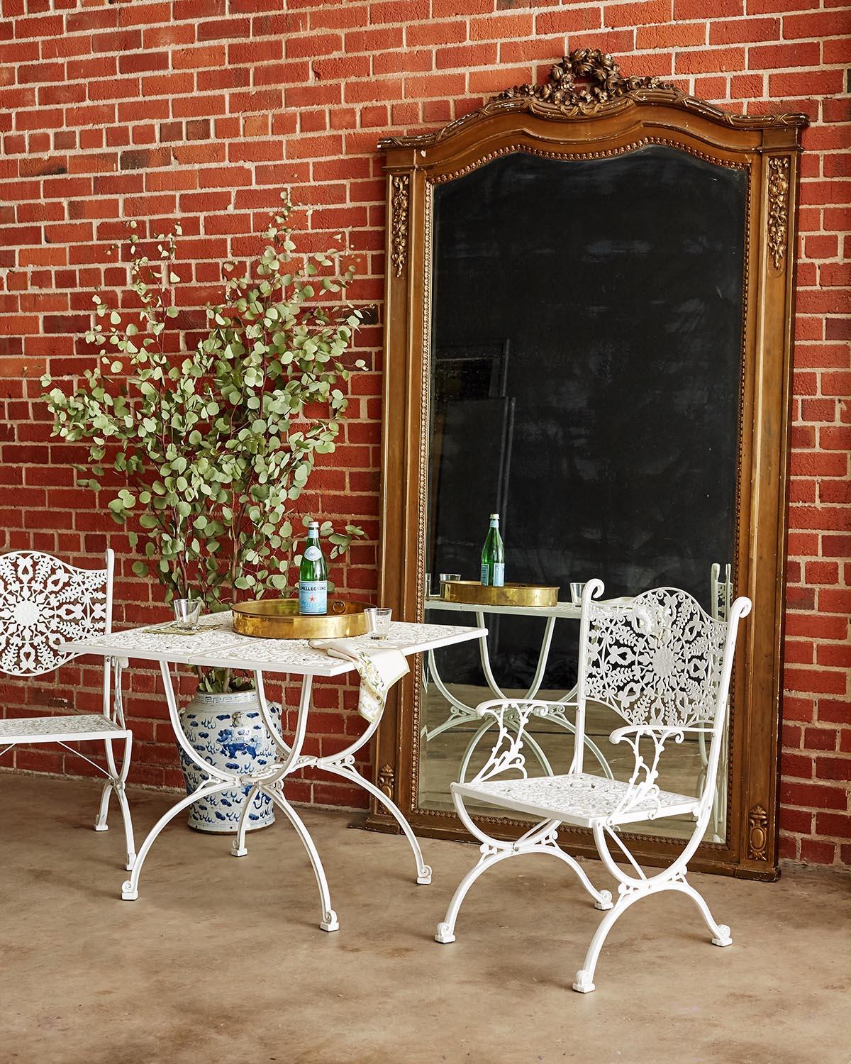 Remarkable set of four aluminum garden patio chairs made in the neoclassical taste. Featuring a delicate seat and back decorated with a foliate sunburst design. The arms, legs, and tops all have scrolled ends and the chairs are supported by curule