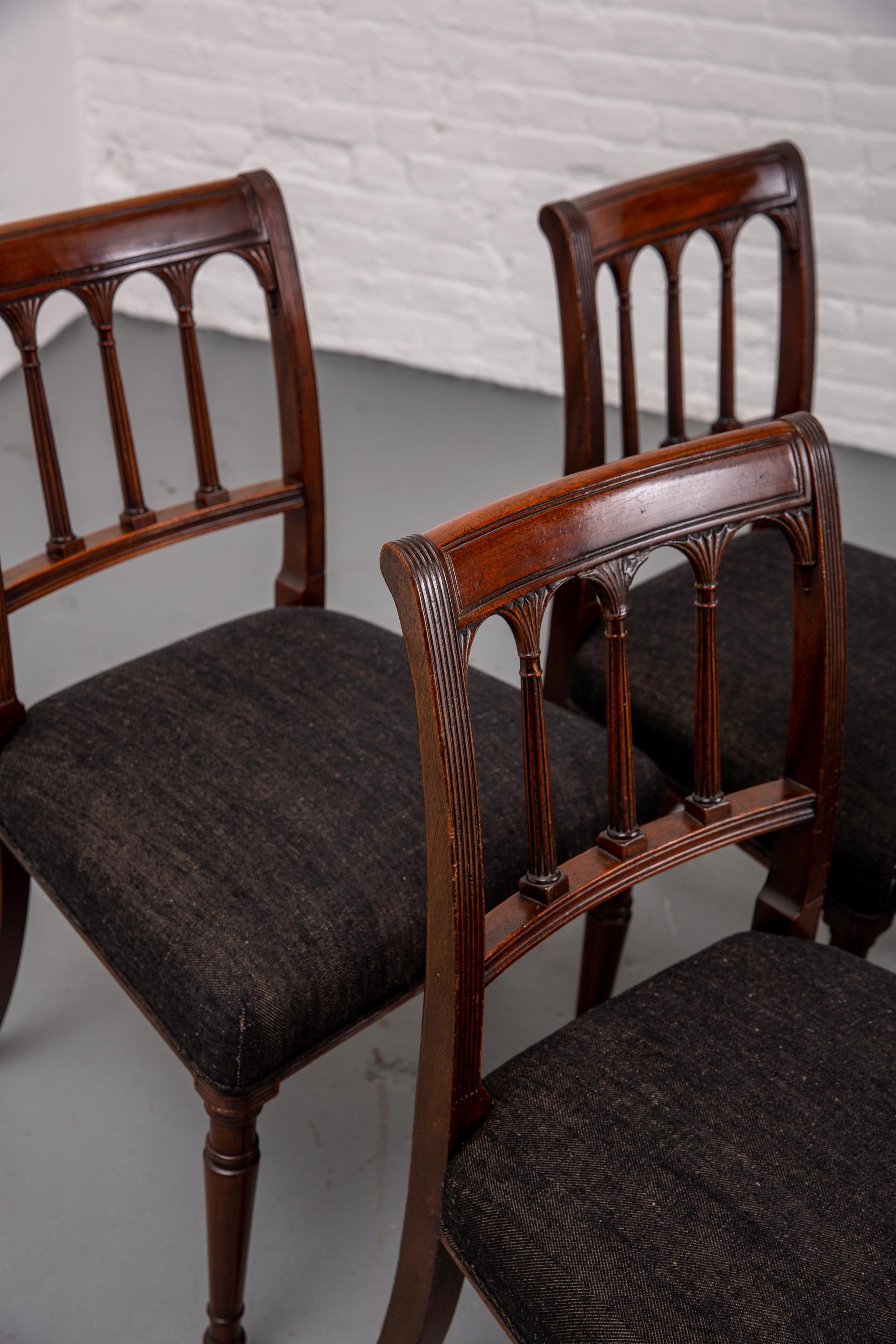 Set of four 19th century mahogany dining chairs with newly upholstered seats. Tapered legs to front. Neoclassical style. Carved column detailing. Marking to wood throughout, please see photos. Newly upholstered in herringbone black/brown fabric.
