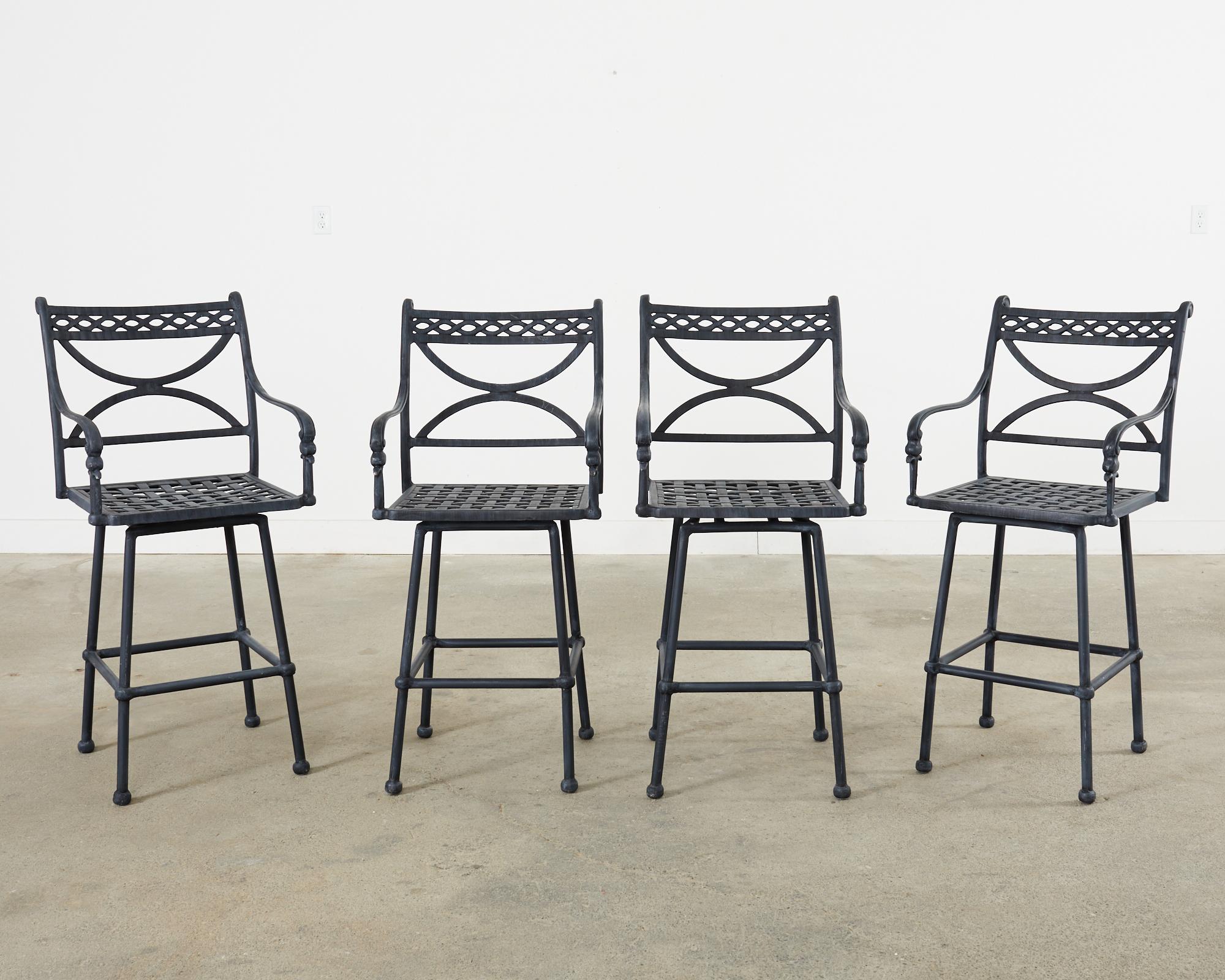 Extraordinary set of four patio and garden swivel bar height barstools constructed from cast aluminum. The stools feature an intentionally aged and faded patina on the soft finish. The backs have a scrolled top and a large x form back splat centered