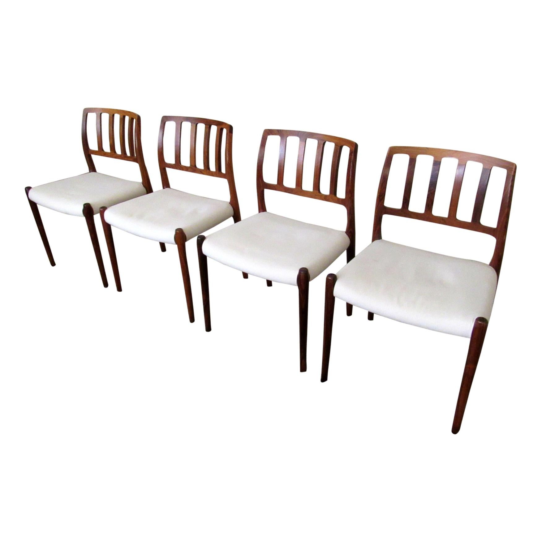 A four-piece set of “Model 83” upholstered rosewood dining chairs designed by Niels Otto Møller for J.L. Møller. Timeless Danish design features solid rosewood frame with smoothly sculpted back and front legs. Branded on the underside with maker’s
