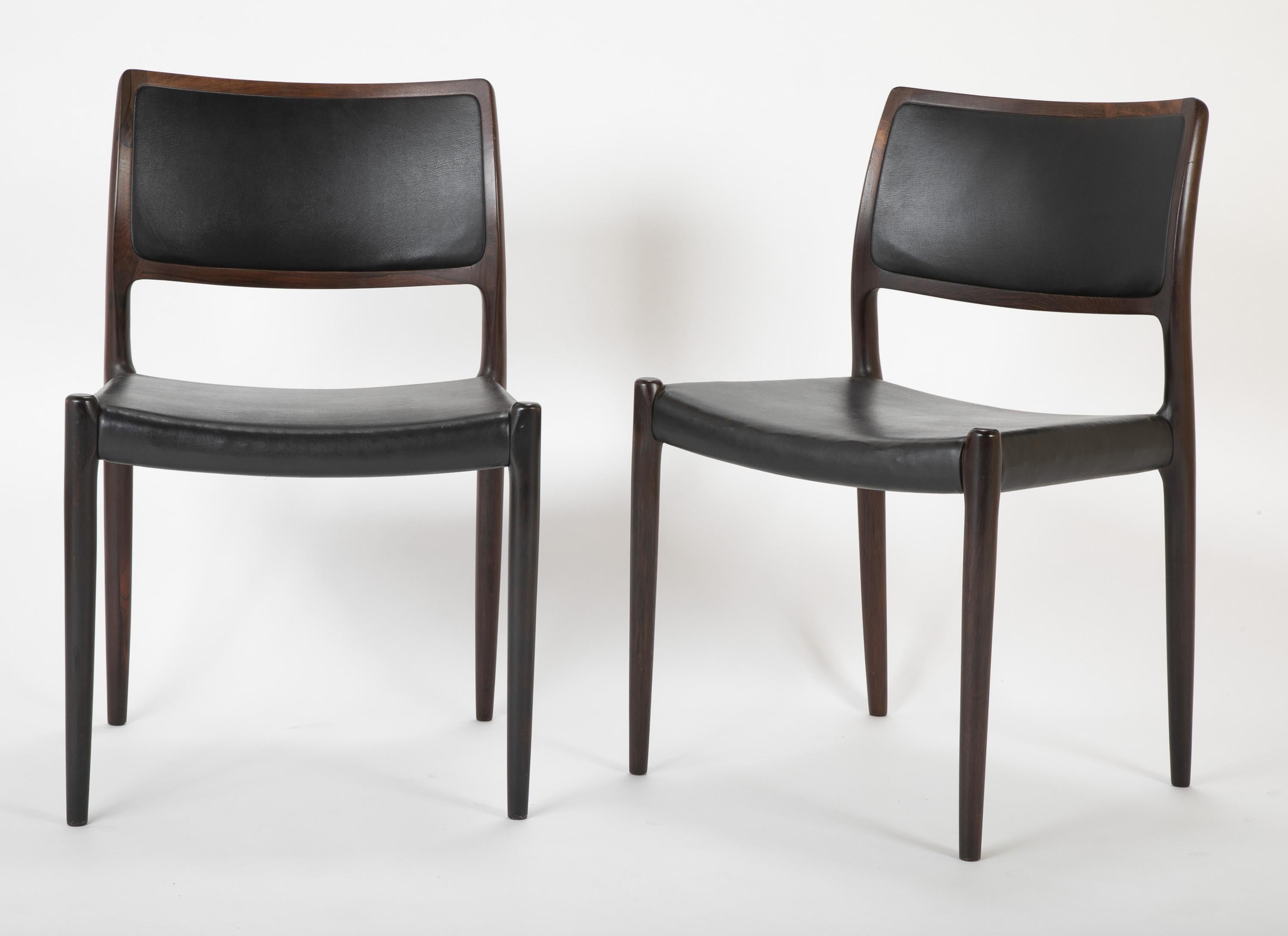 A set of four Danish Niels Moller dining chairs upholstered in black leatherette.