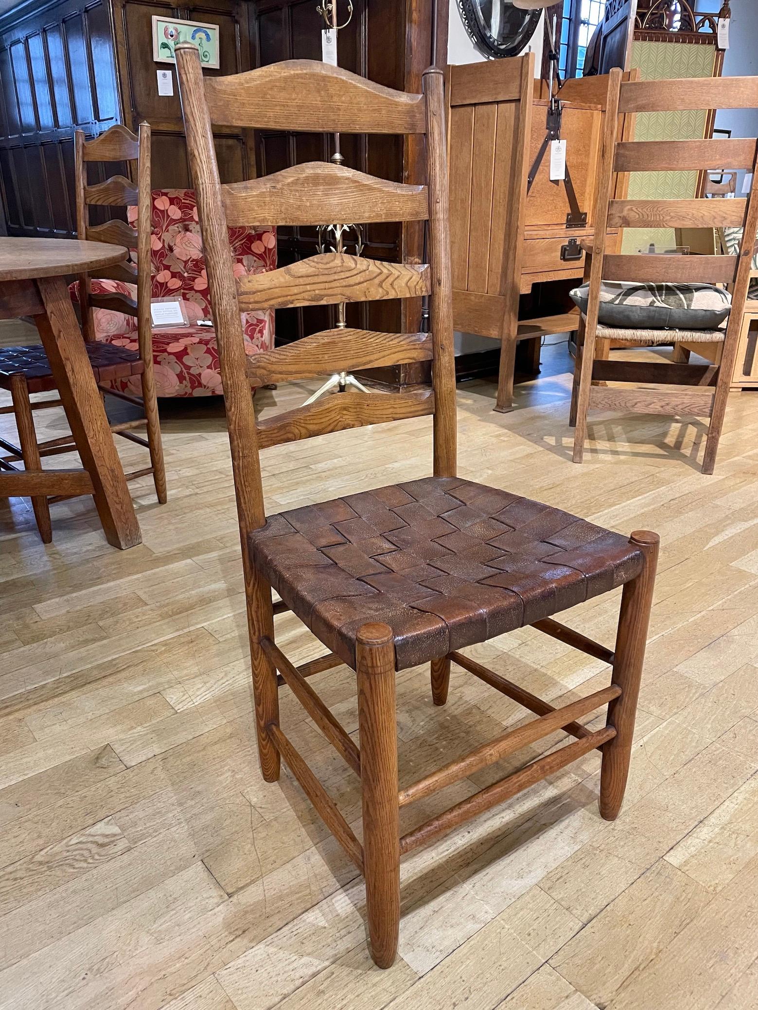 Rare set of four Arts and Crafts Cotswold School ladder back dining chairs by Gordon Russell. Ash with woven leather seats. 
We have cleaned the chairs with wax and have replaced 3 of the seats traditionally using high quality natural leather hide