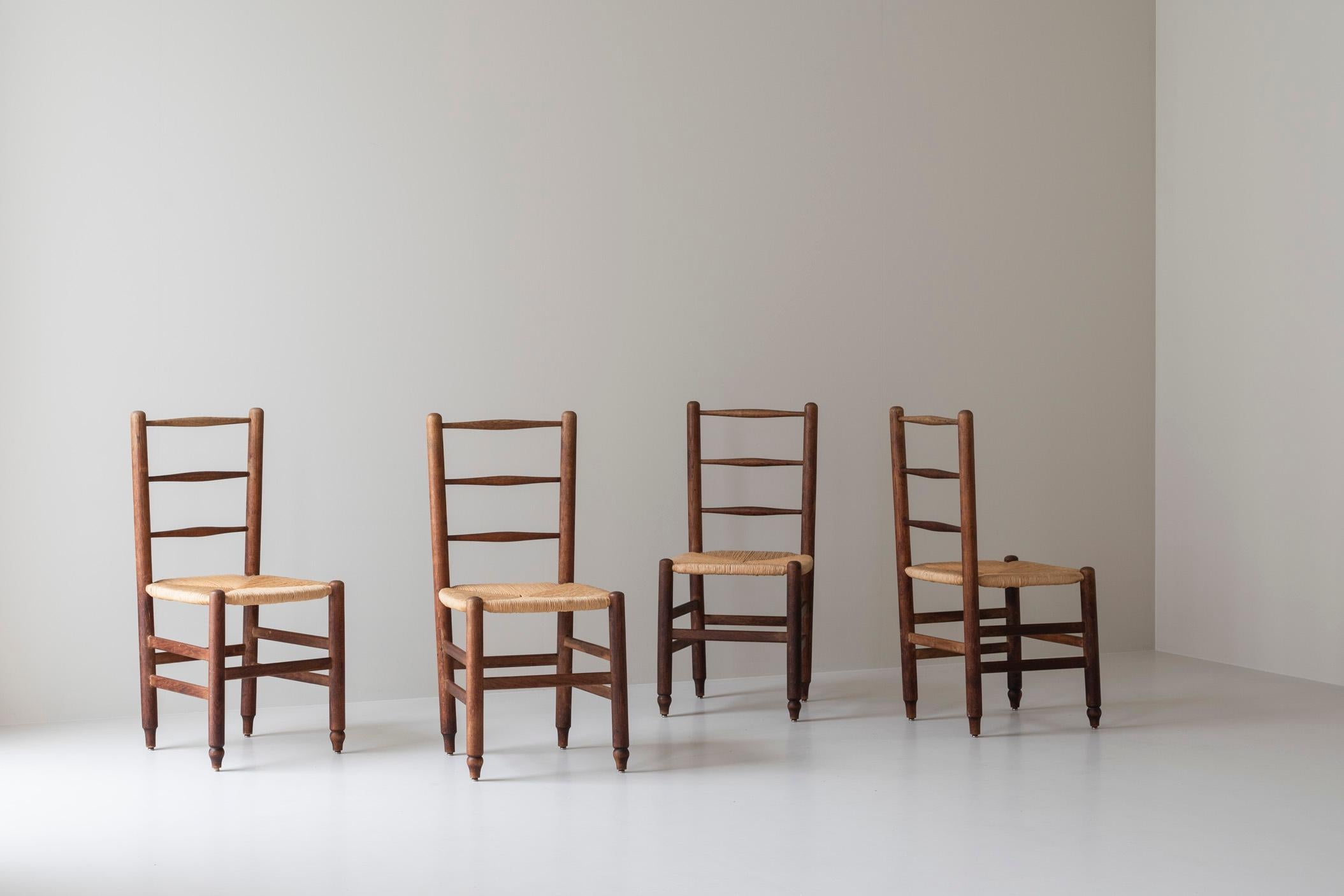 Set di quattro sedie da pranzo di provenienza francese, risalenti agli anni '60. Queste sedie sono caratterizzate da una solida struttura in Oak, composta da gambe dritte e spesse collegate tra loro da sottili doghe orizzontali. I sedili sono fatti