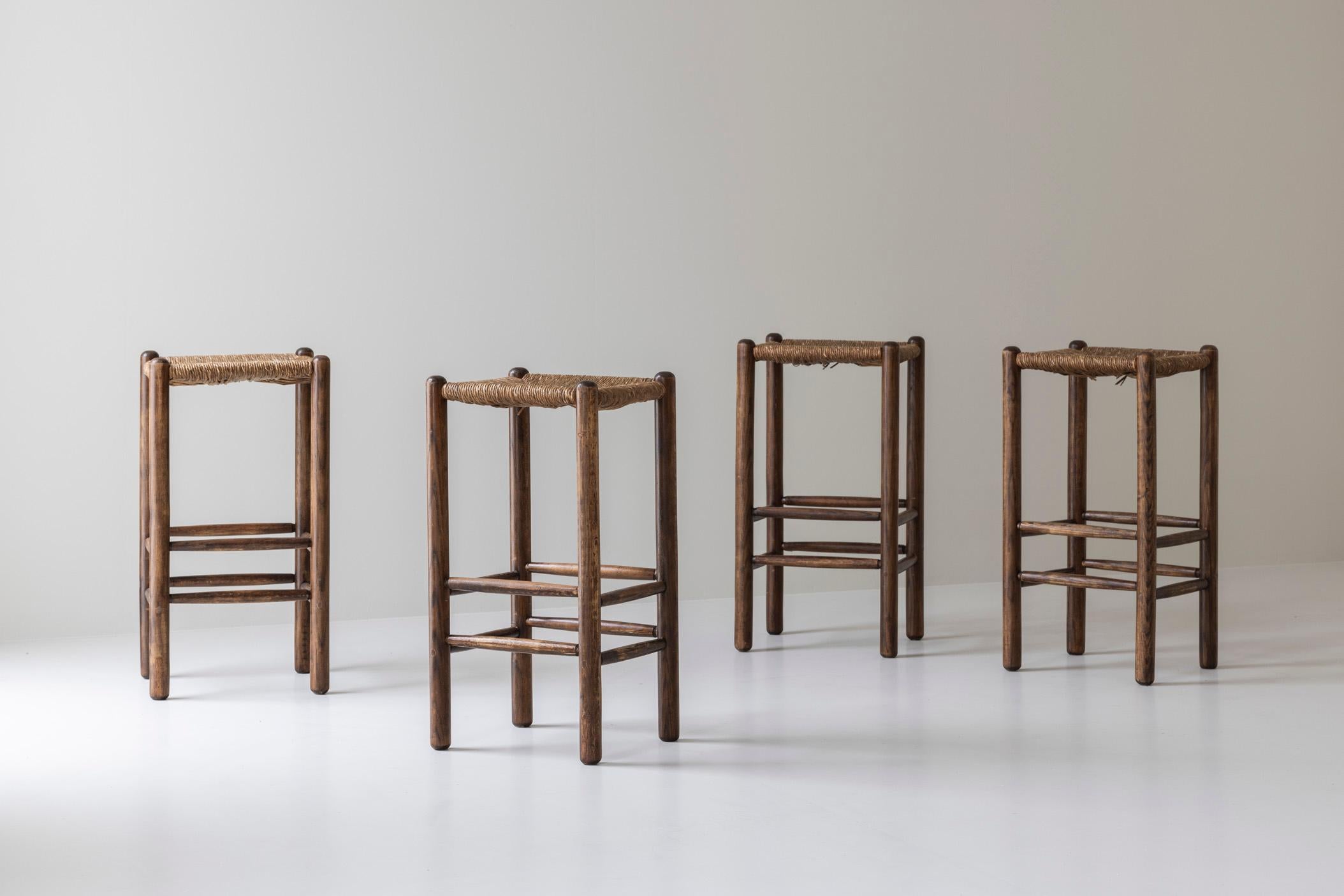 Grazioso set di quattro sgabelli da bar rustici acquistati in Francia e risalenti agli anni Sessanta. Questi sgabelli alti hanno una struttura in Oak tinto scuro, composta da gambe dritte e spesse collegate tra loro da sottili doghe orizzontali. I