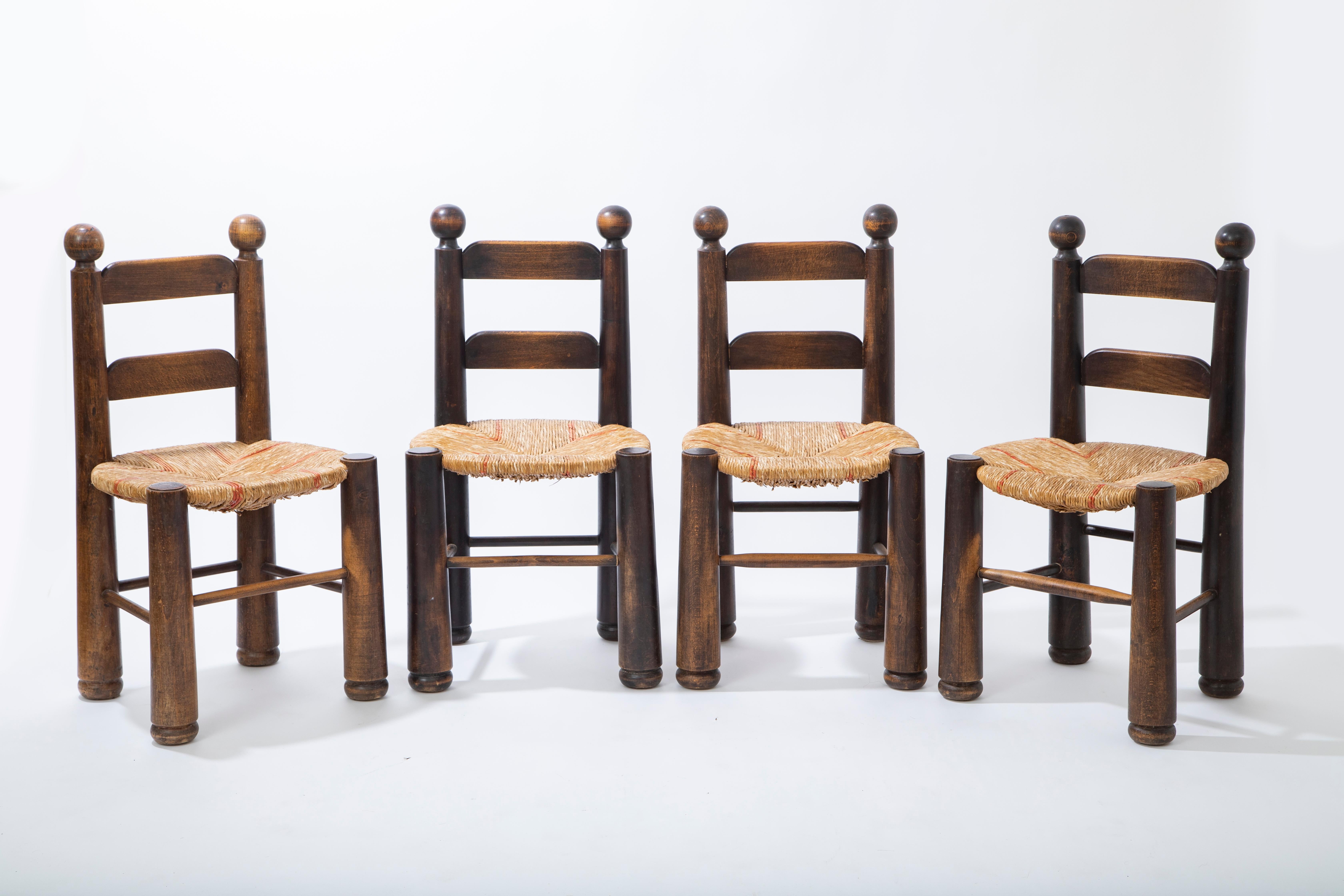 Set of four oak dining chairs with rush seats by Charles Dudouyt
 Ladder-back carved oak wood 
Featuring woven rush seats with some red accents 
Original condition and patina
 Structurally sound for everyday use.
France circa